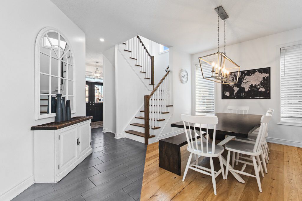Elegant entryway with white staircase, wainscoting, mixed hardwood floors, and a chandelier over a dining nook.