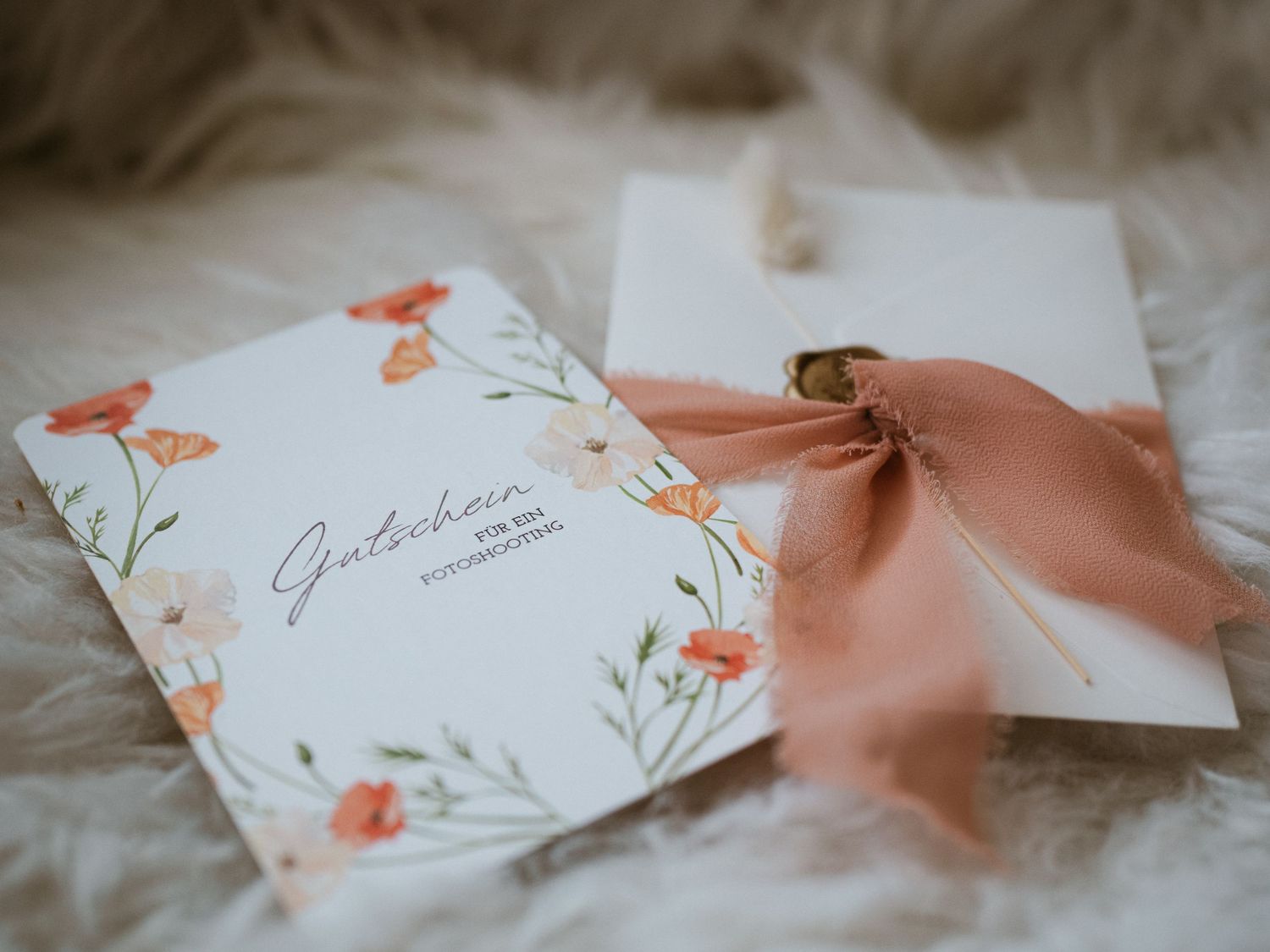 Wedding invitation card with delicate orange floral design and peach silk ribbon on white textured background.