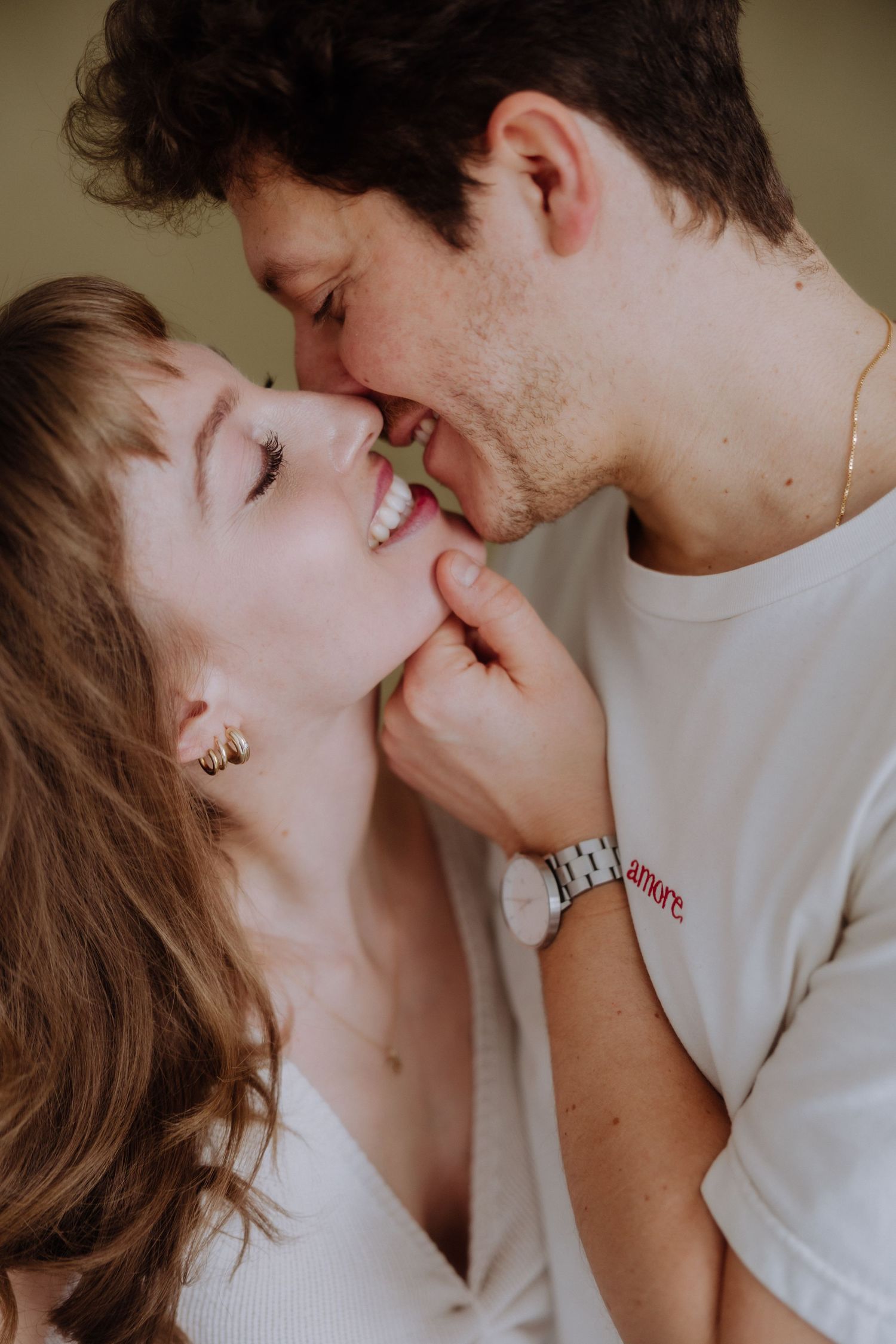 A romantic couple sharing an intimate moment together while smiling and embracing in soft lighting.