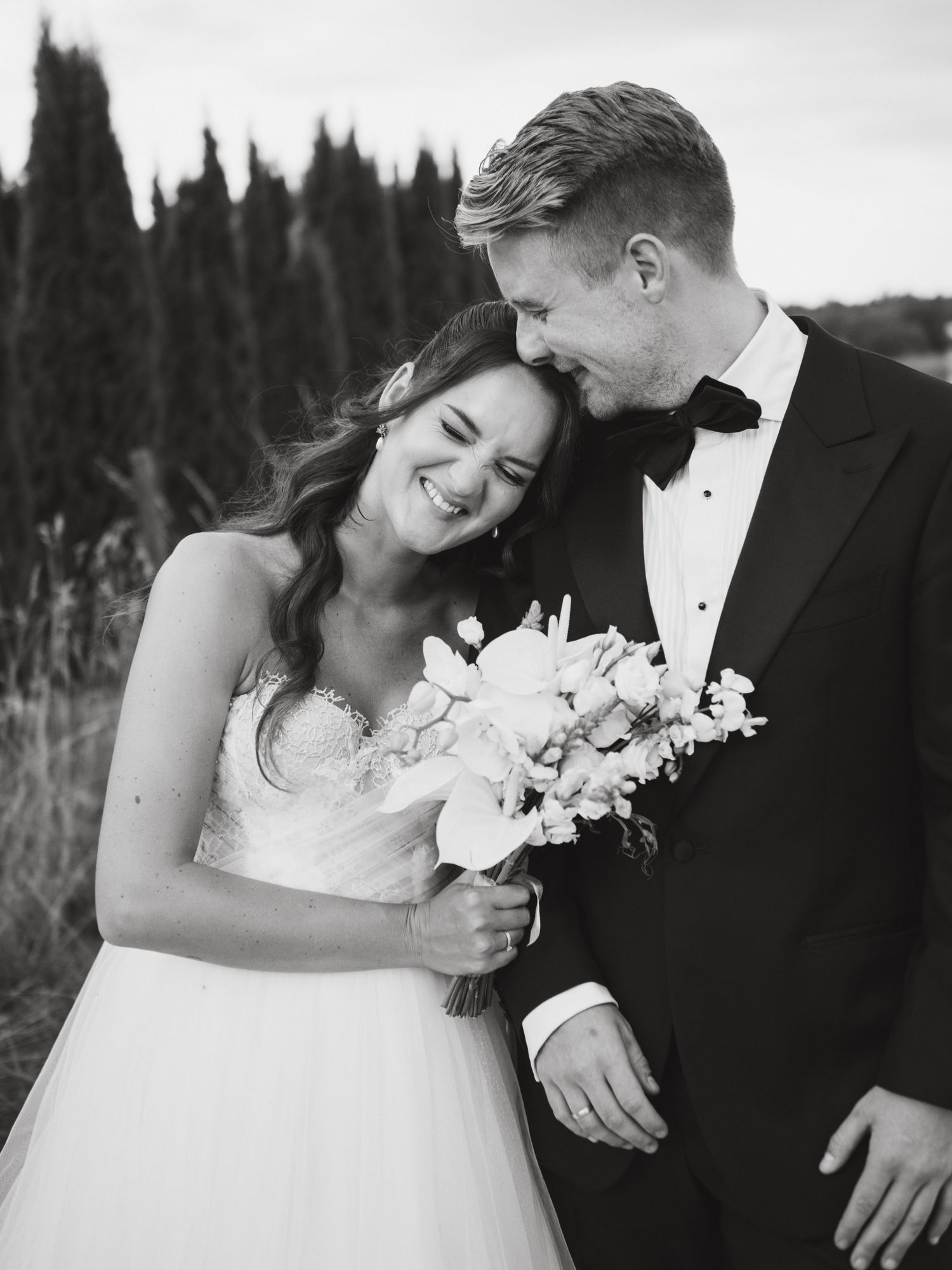A romantic black and white wedding photo series showing tender moments between newlyweds with white flowers.