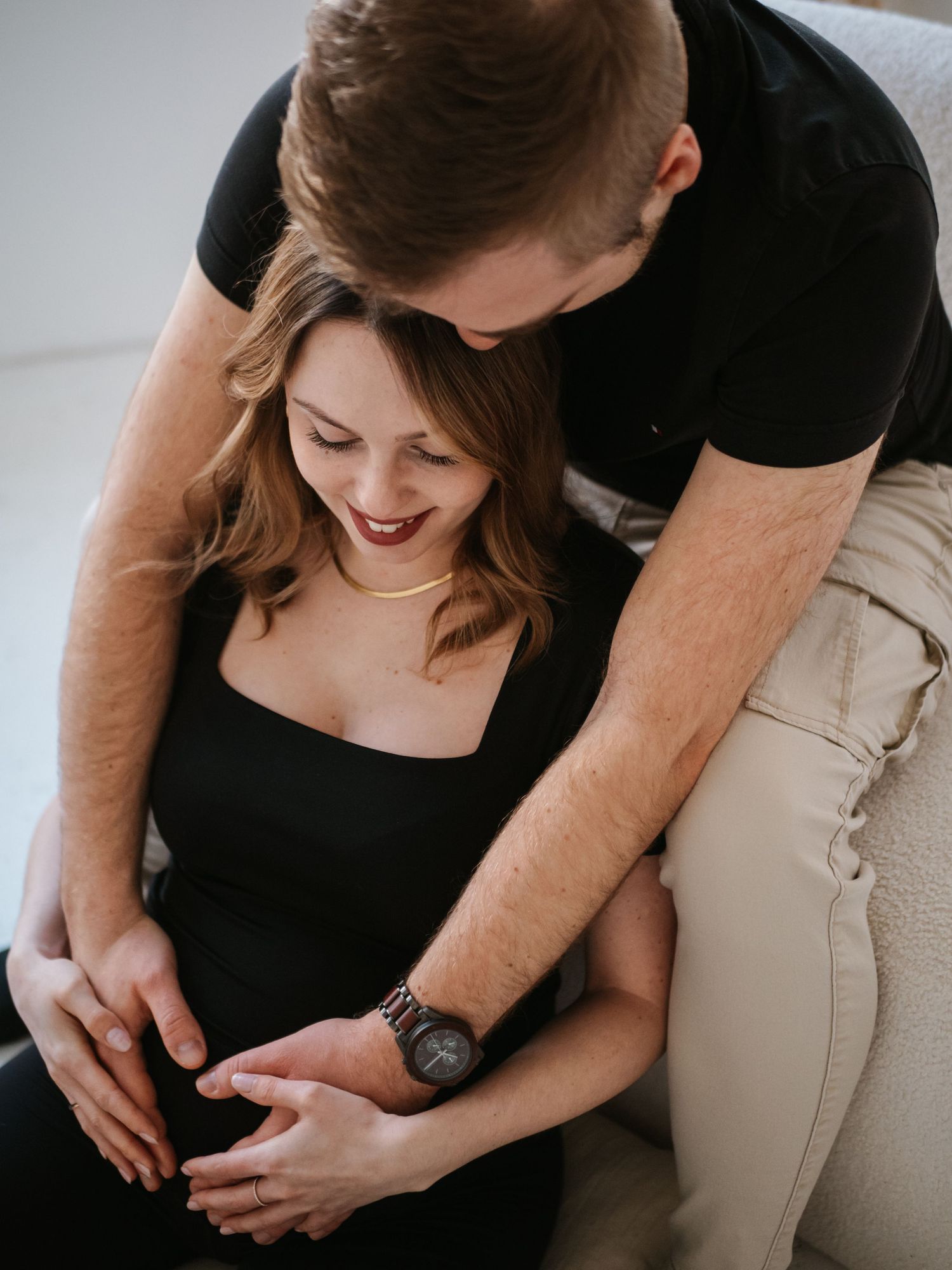 Intimate close-up shots of couple embracing and holding hands in black and beige outfits.