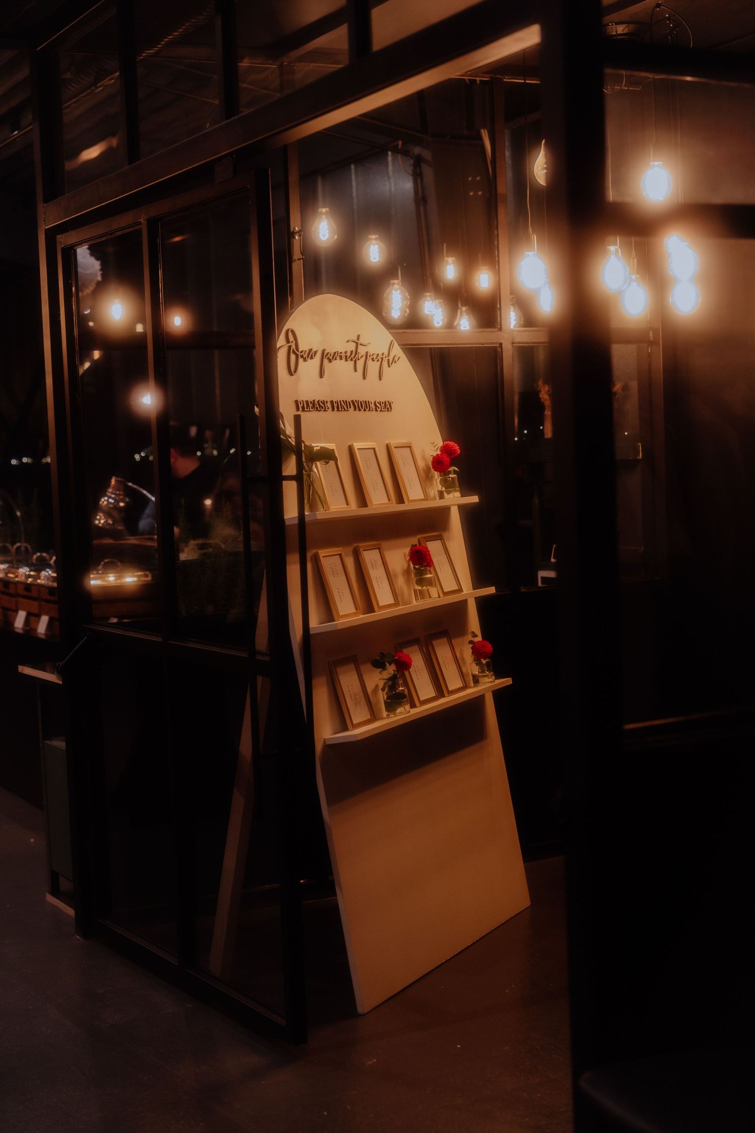 A wooden book display stand with warm lighting showcases books in a cozy, dimly lit interior space.