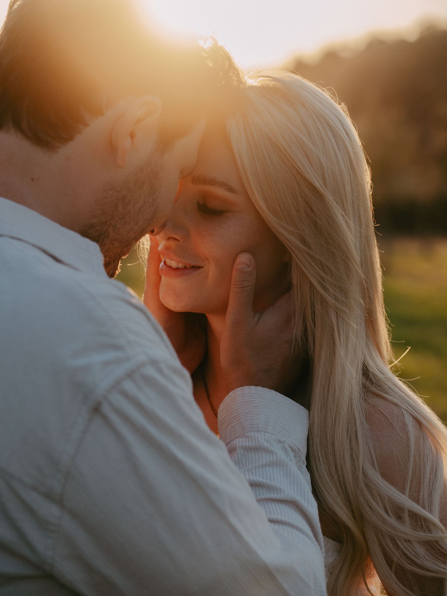 Romantic couple embraces during golden hour sunset creating intimate silhouettes against warm glowing sky.