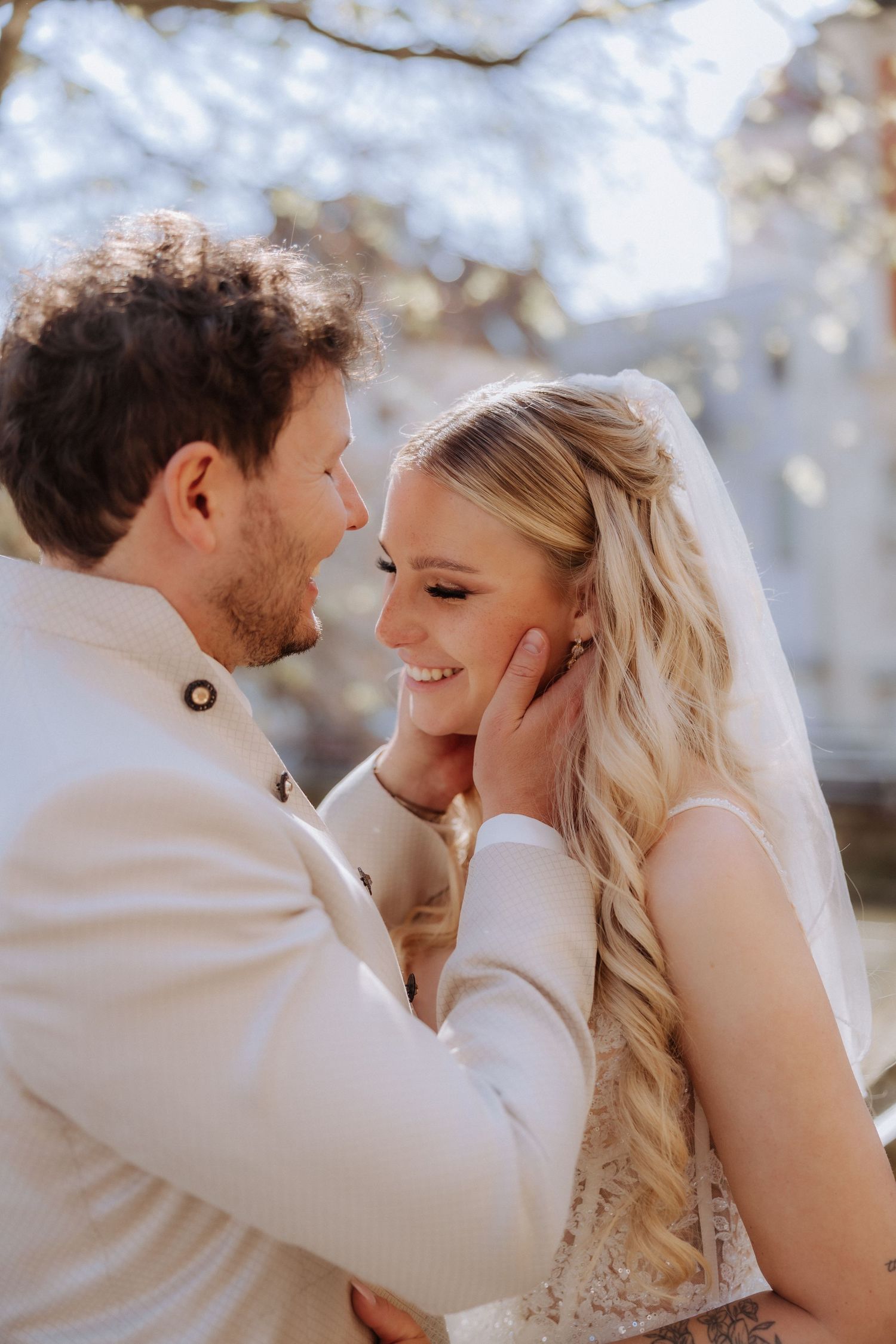 A tender wedding moment captured between newlyweds sharing an intimate embrace under soft natural lighting.