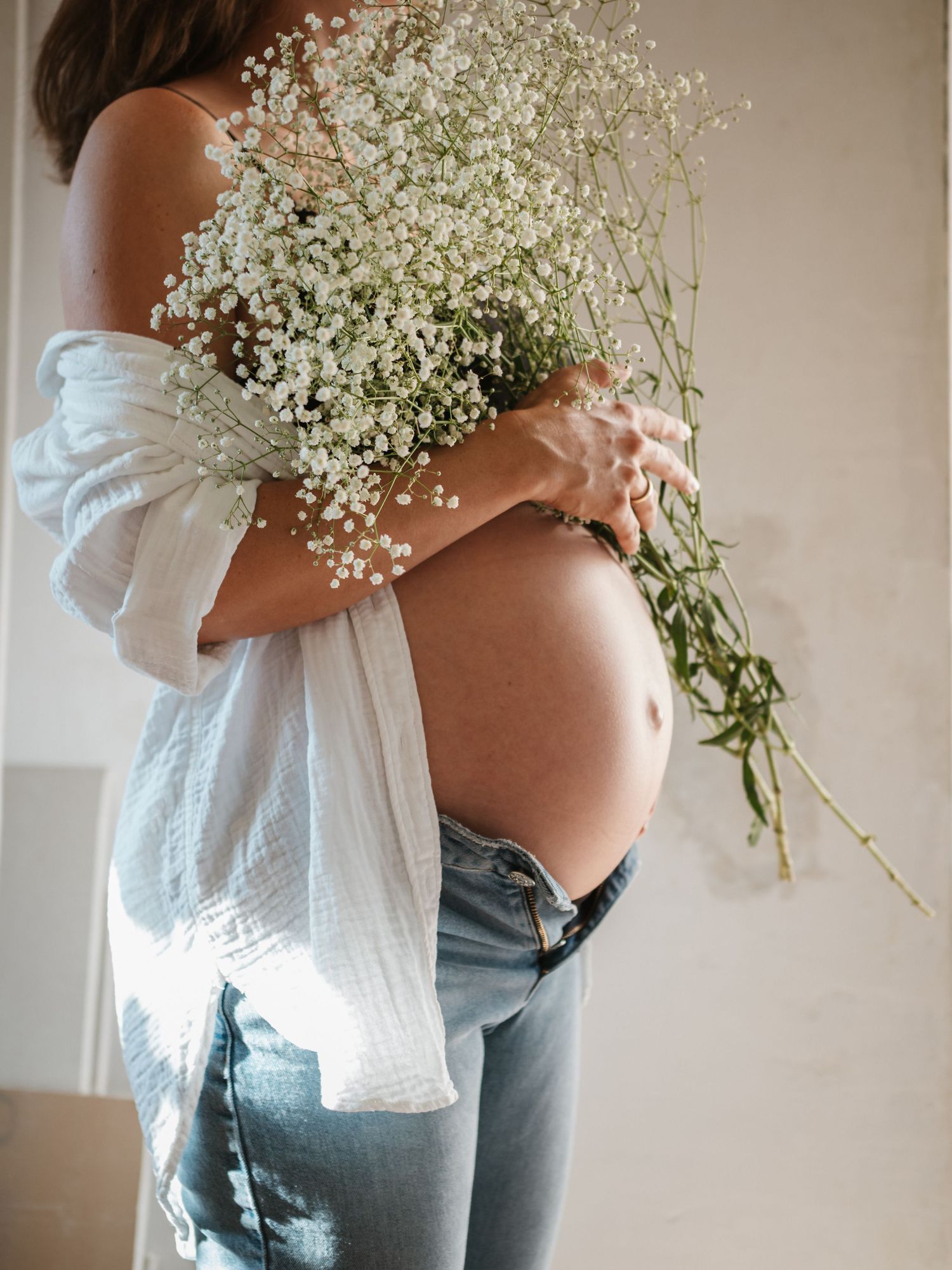 A series of images showing a person in a gray top holding a delicate bouquet of baby's breath flowers against a neutral wall.