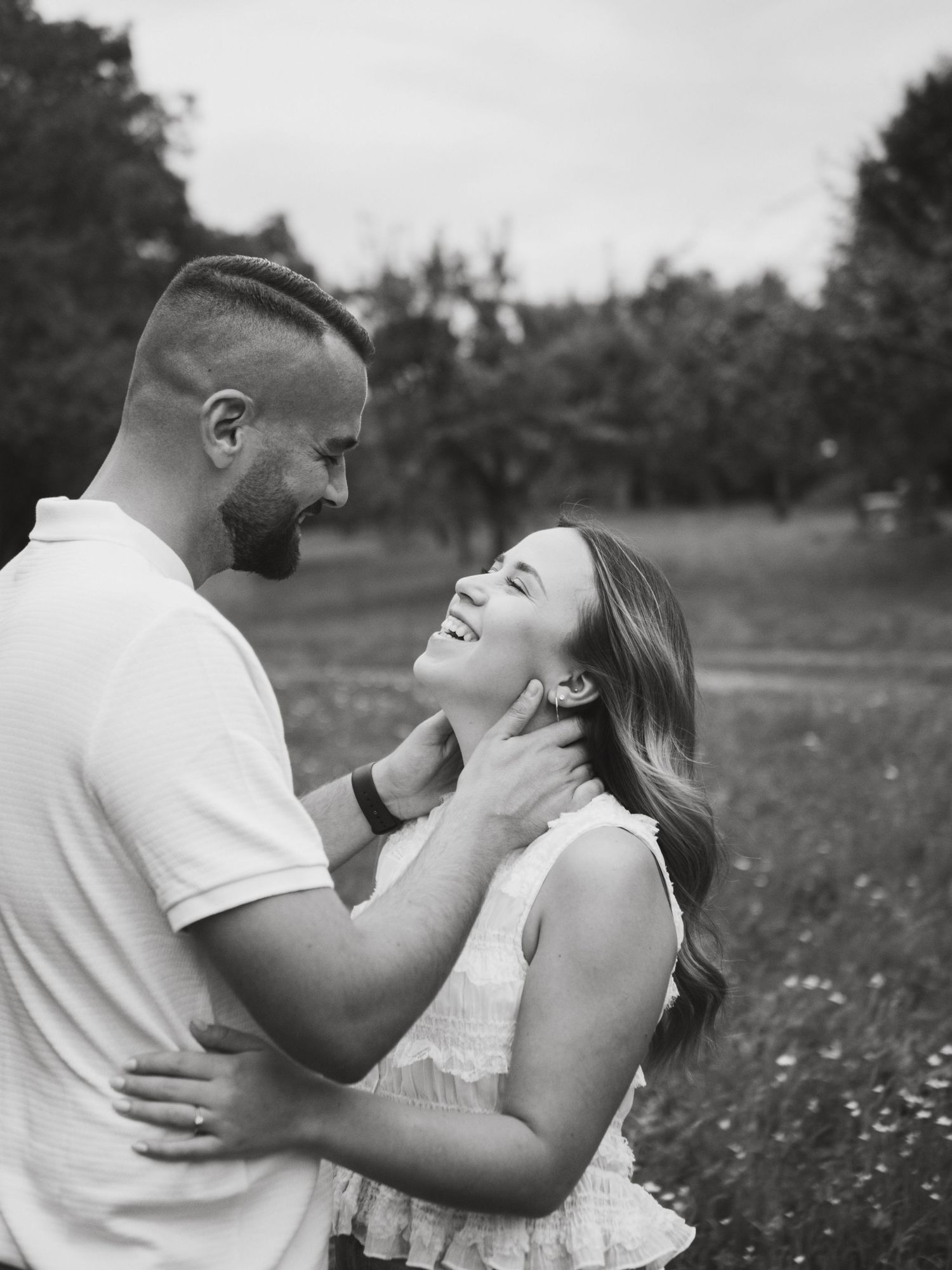 A couple shares tender moments in a field of wildflowers, captured in black and white across four romantic frames.
