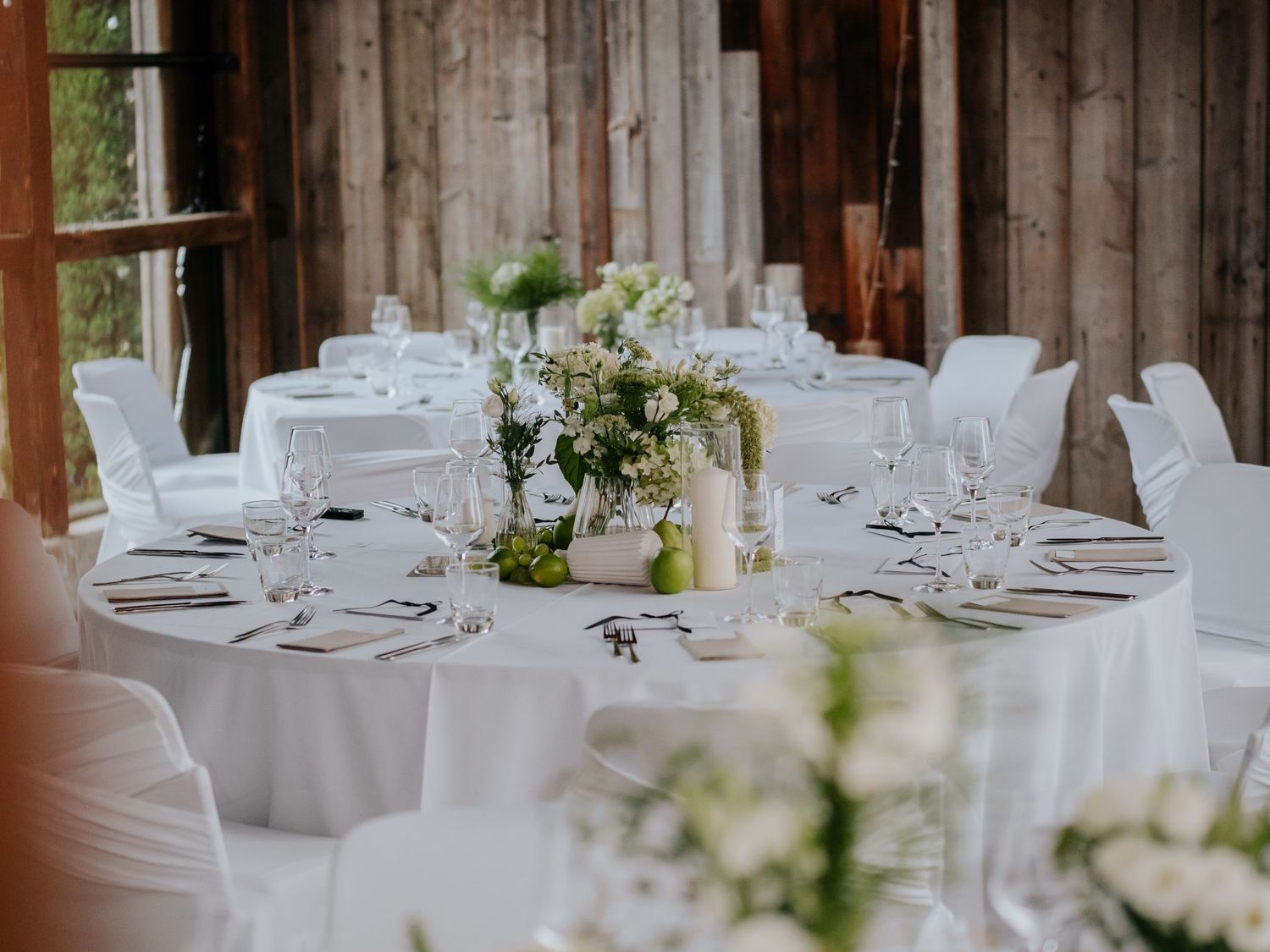 Elegant wedding reception venue with rustic wood walls, white tablecloths, and delicate floral centerpieces.