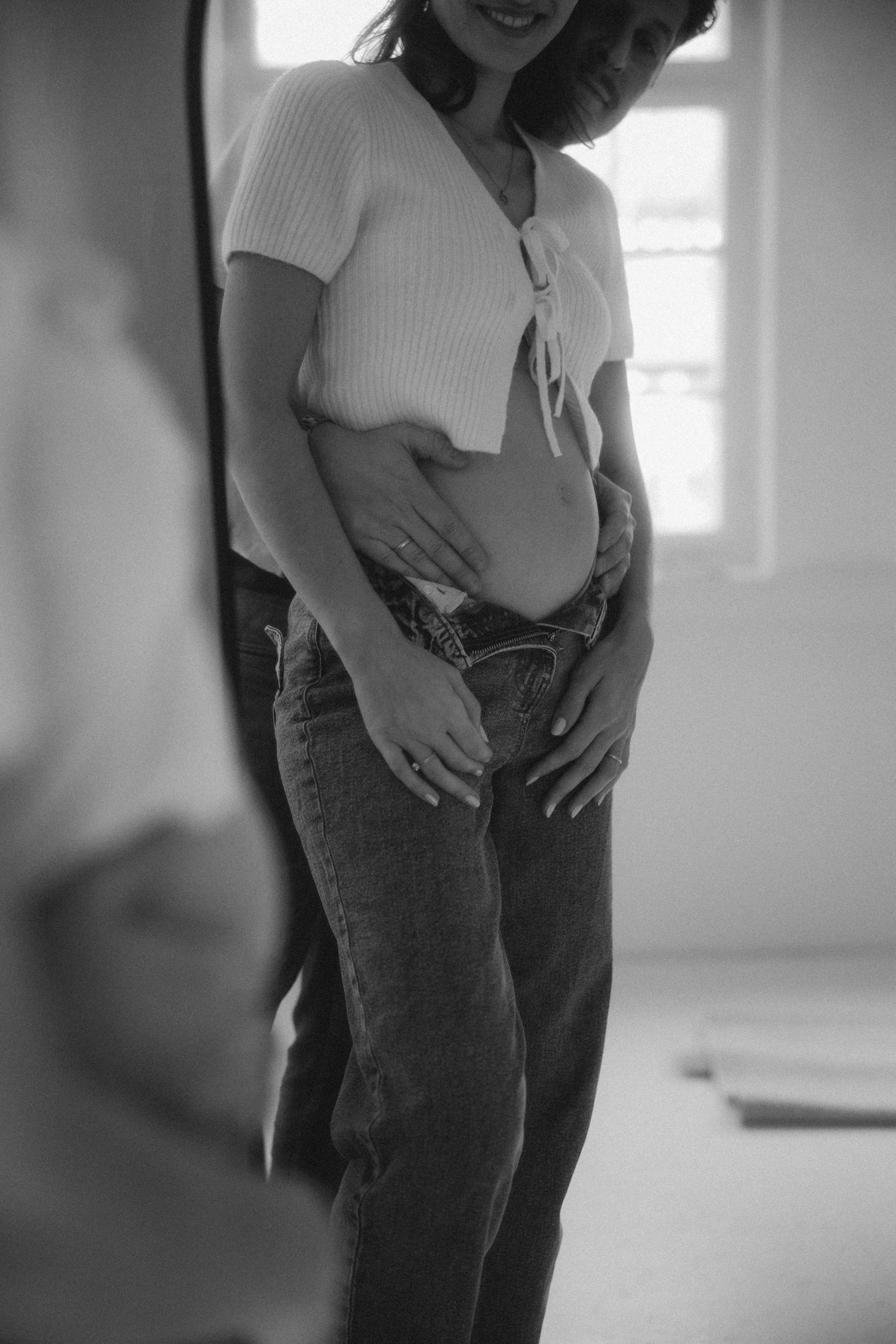 A series of black and white photos showing someone in a white shirt and jeans holding their stomach.