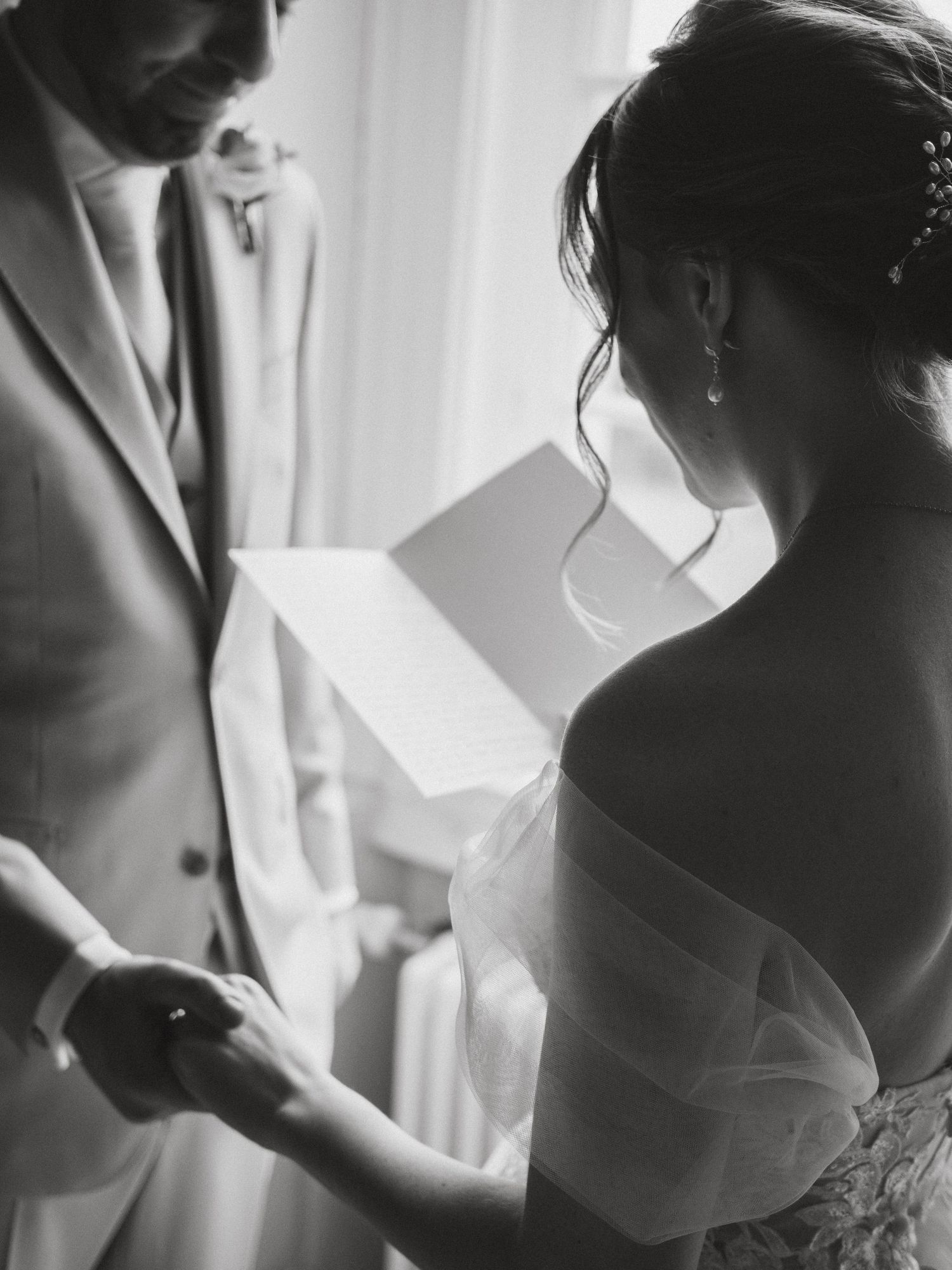 Black and white artistic wedding photos showing intimate getting ready moments in silhouette by a window.