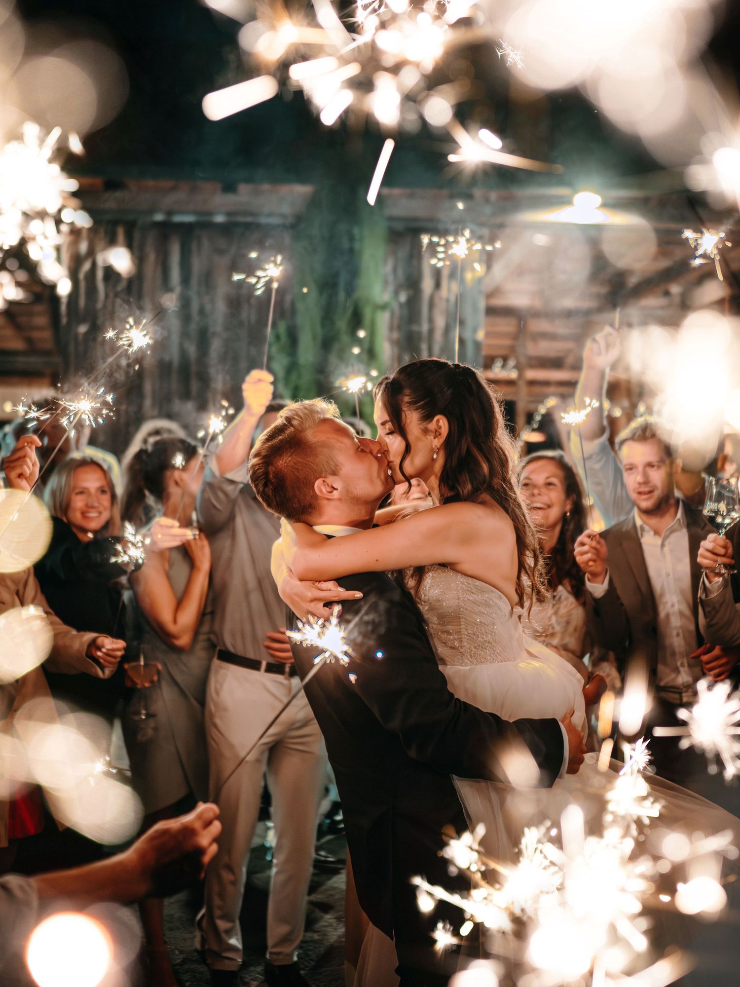 Celebration scene with sparklers creating magical bokeh effects as people dance and embrace.