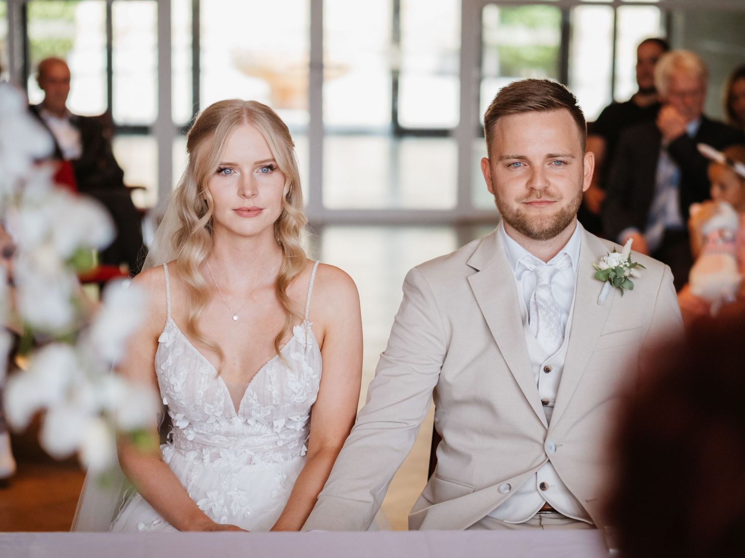 Wedding ceremony captures in light-filled venue with elegant decor and formal attire.