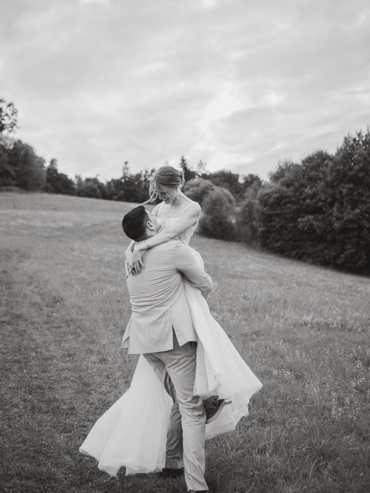 A romantic black and white photo sequence shows a couple spinning joyfully together in a grassy meadow.