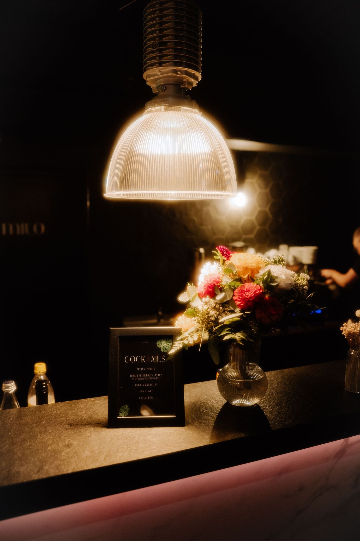 Moody bar counter with illuminated glass dome lights and floral arrangements creating an intimate ambiance.