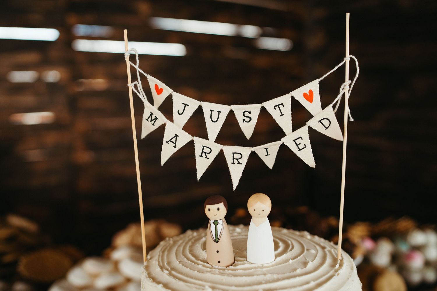 Rustic cake topper with 'Just Married' bunting banner on white frosted dessert.