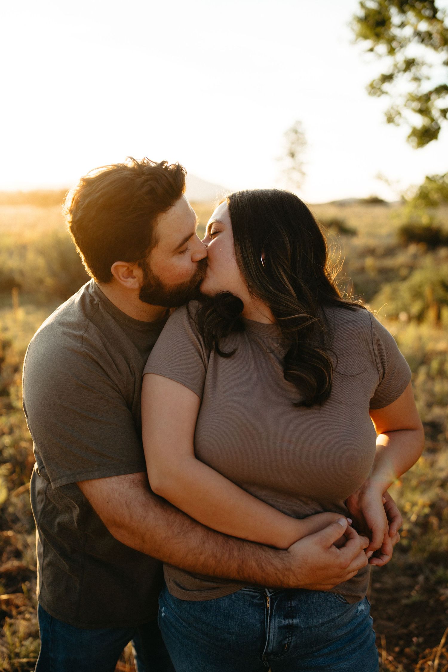 A romantic sunset moment shared between a couple in casual attire outdoors.