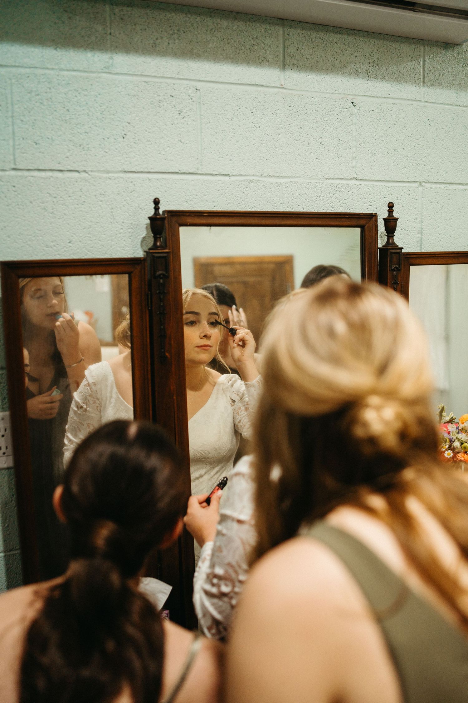 Getting ready scene reflected in vintage mirrors showing wedding preparations.