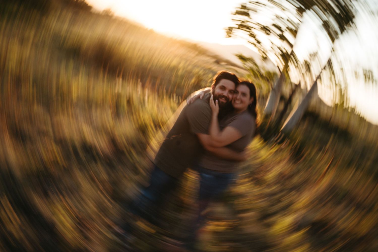 A blurred motion photo of a couple embracing outdoors with a swirling background effect.