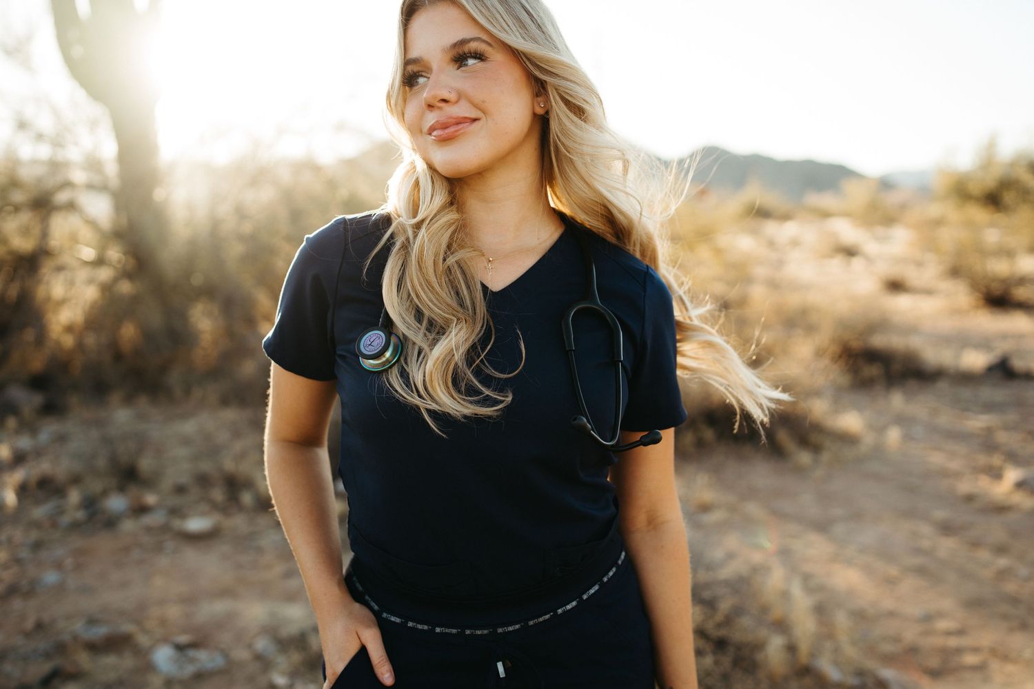Person in black t-shirt smiling in desert setting during golden hour.