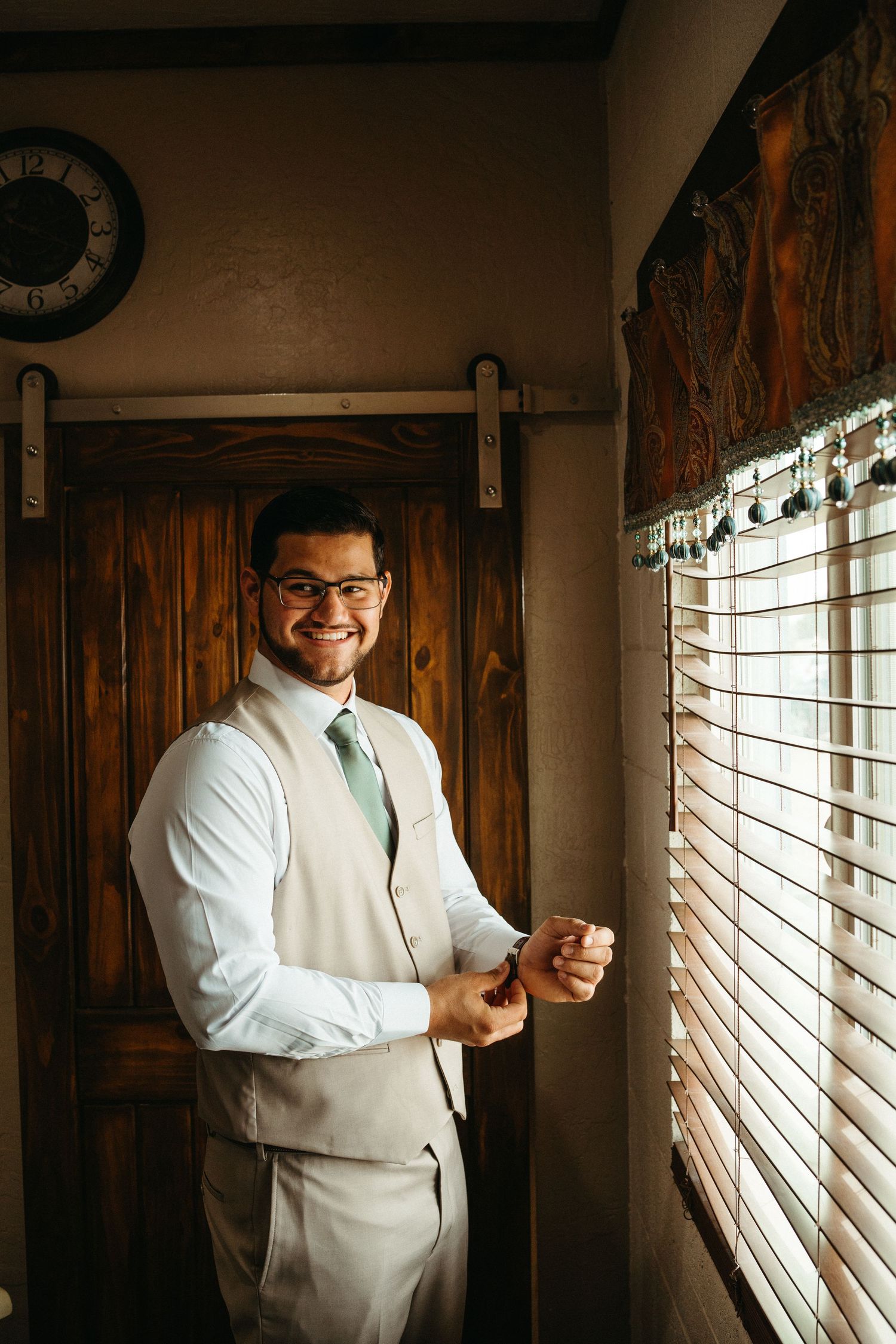 Wedding preparation scene with natural window light and rustic wooden door.