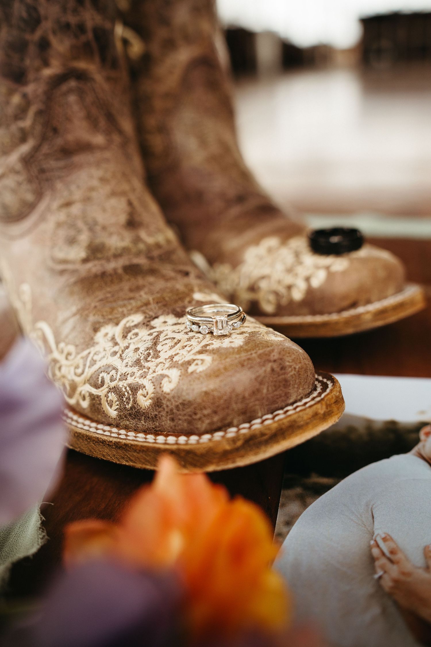 Close-up of ornate western boots with floral embroidery and wedding rings.