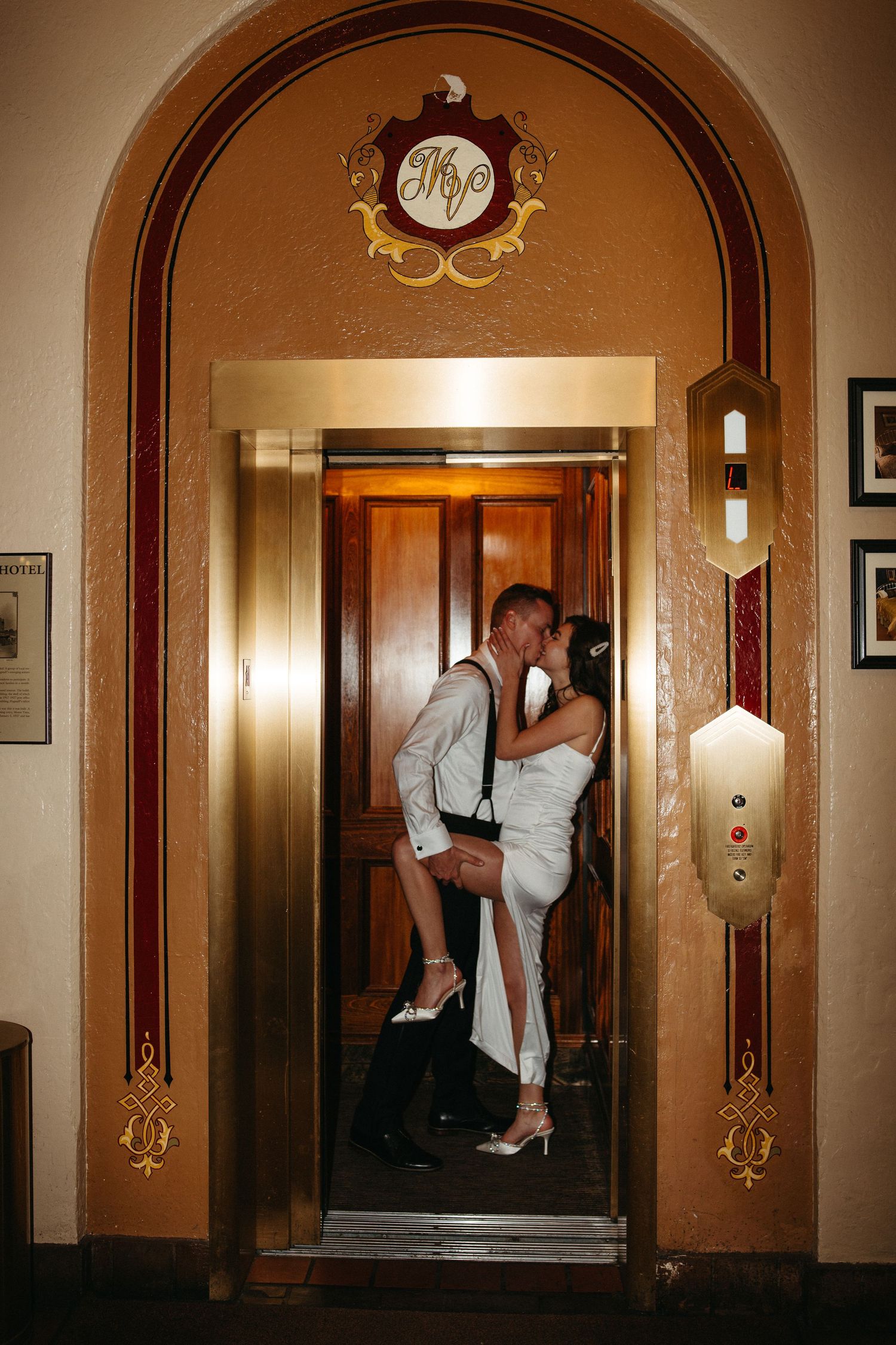 Romantic moment captured in ornate gold elevator doorway of historic building.