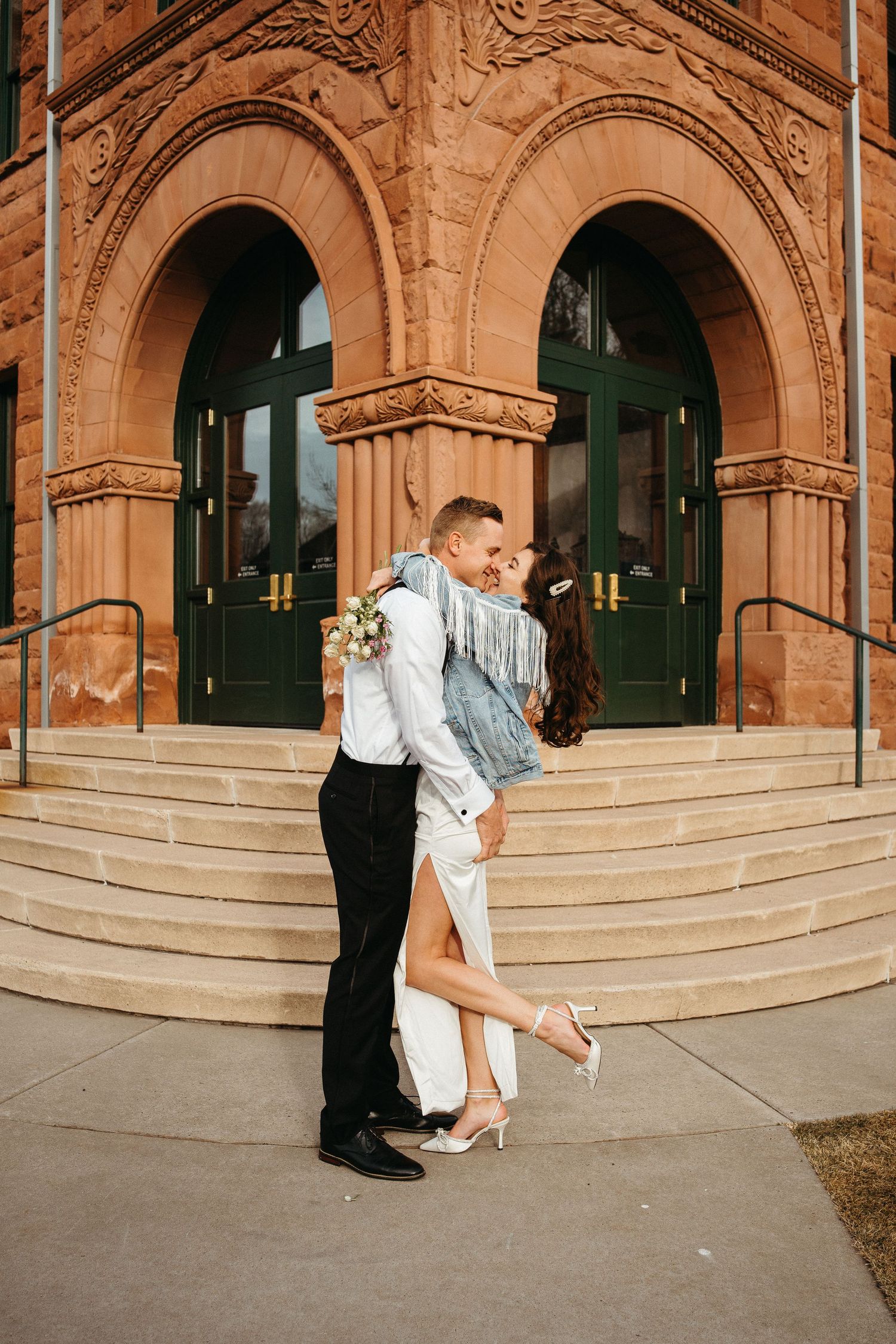 A romantic embrace on the steps of a historic building with grand architecture.