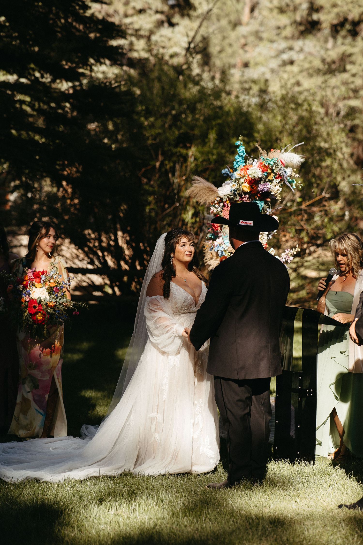 A wedding ceremony in a sunlit outdoor garden setting with vibrant floral arrangements and flowing white dress.