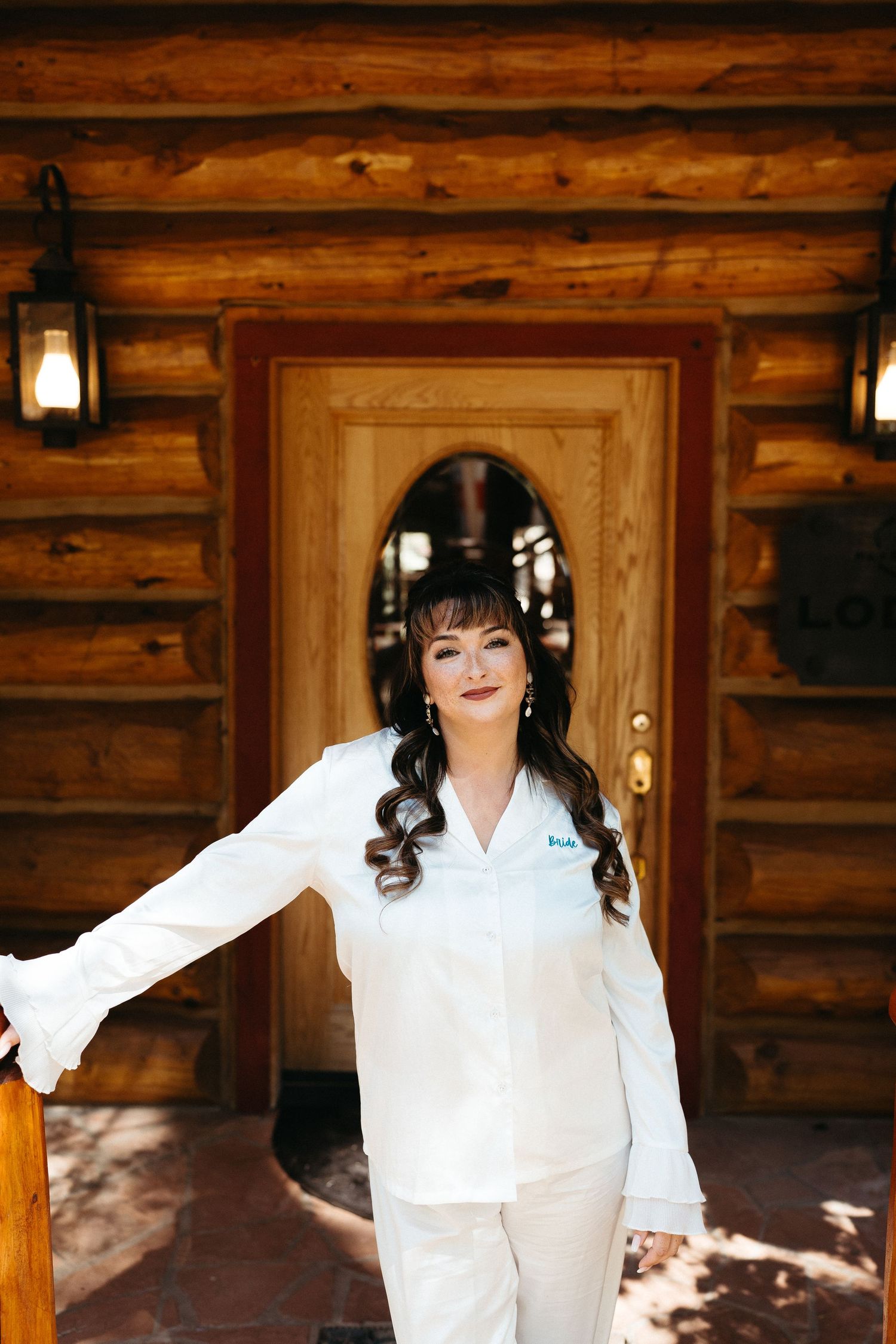 A person in a white dress poses in front of a rustic wooden cabin in a sequence of candid shots.