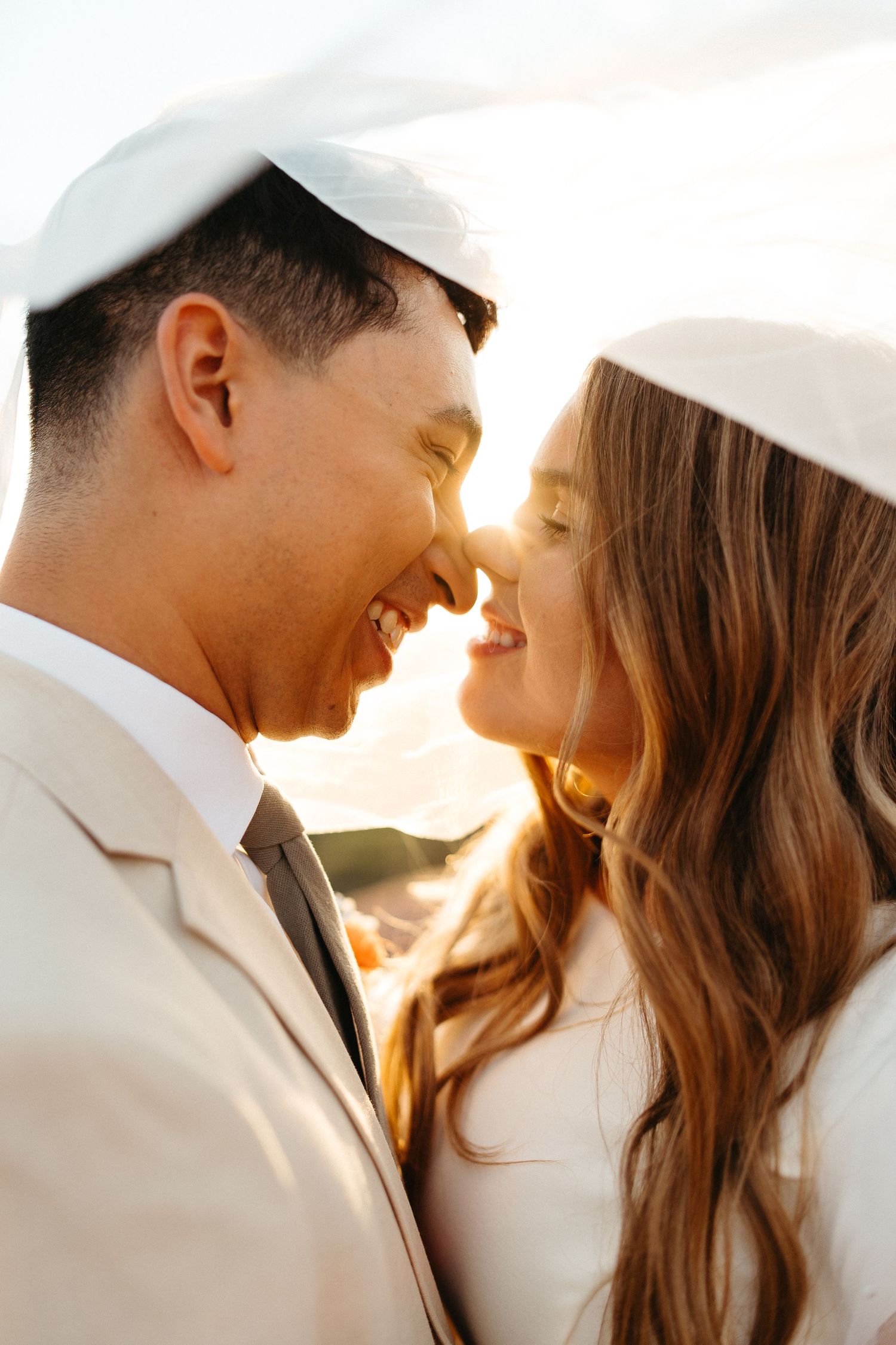 Close-up intimate moment of couple in white attire during golden hour.
