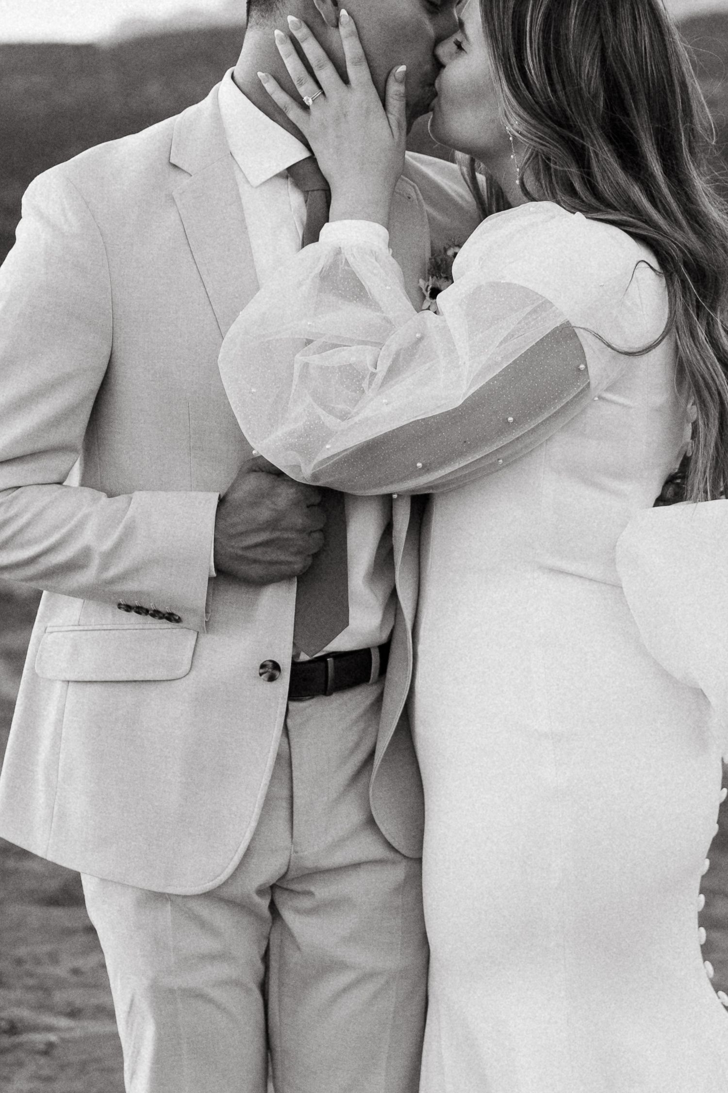 Intimate black and white portrait of couple in light-colored formal attire.