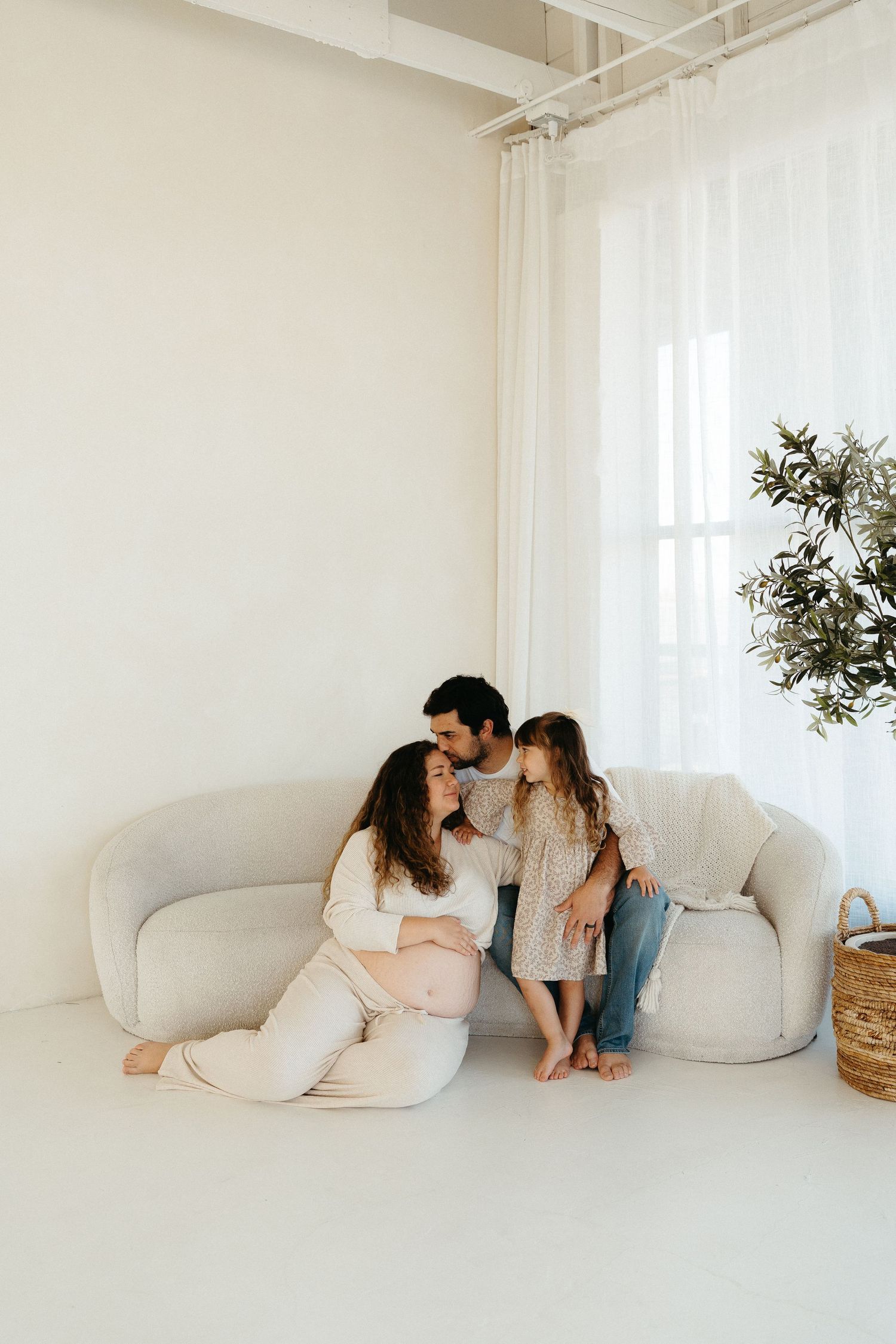 Three minimalist photos of a couple sitting together on a white couch in a bright, airy room with natural light streaming in.