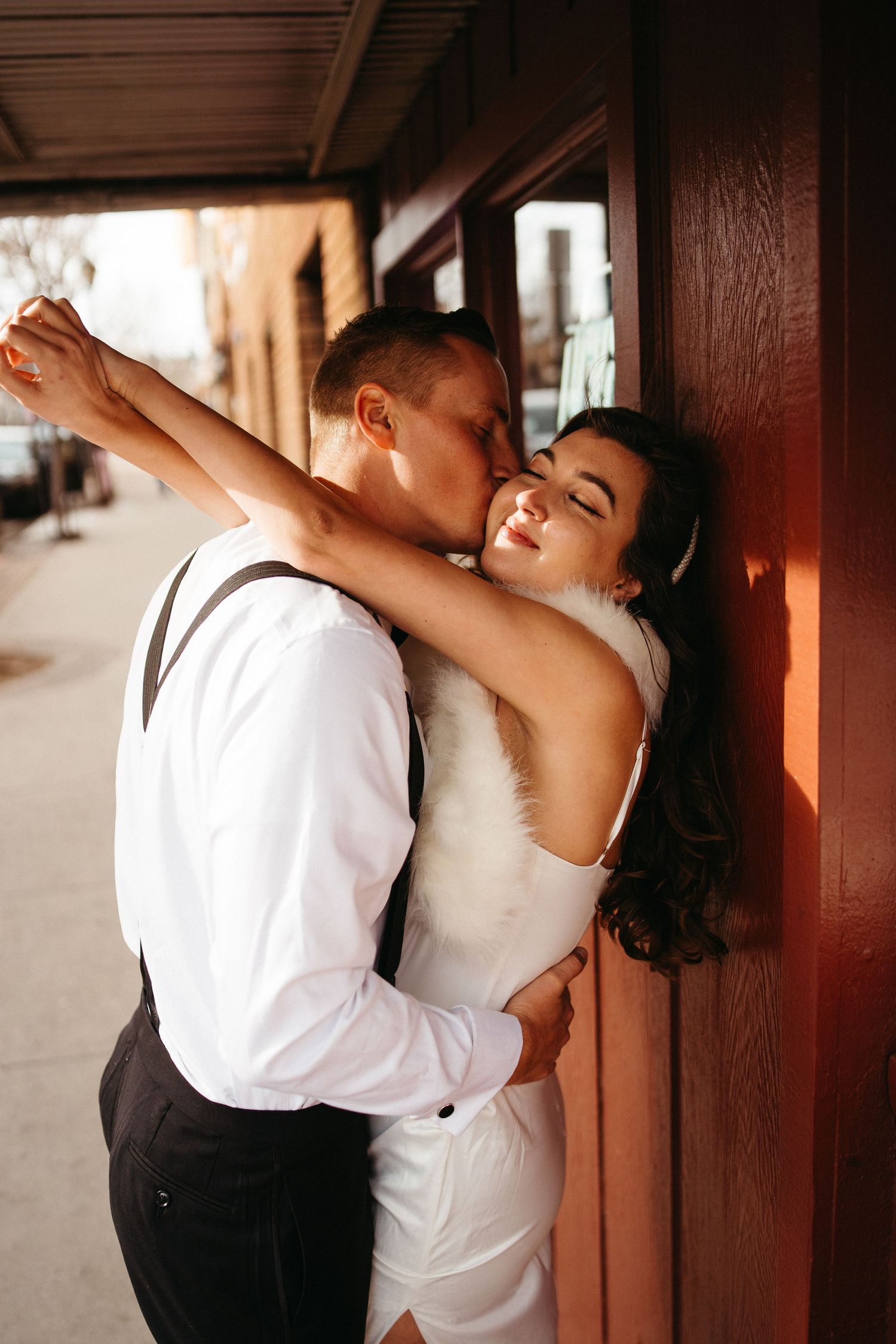 An intimate moment captured between a couple in formal attire against a brick wall.