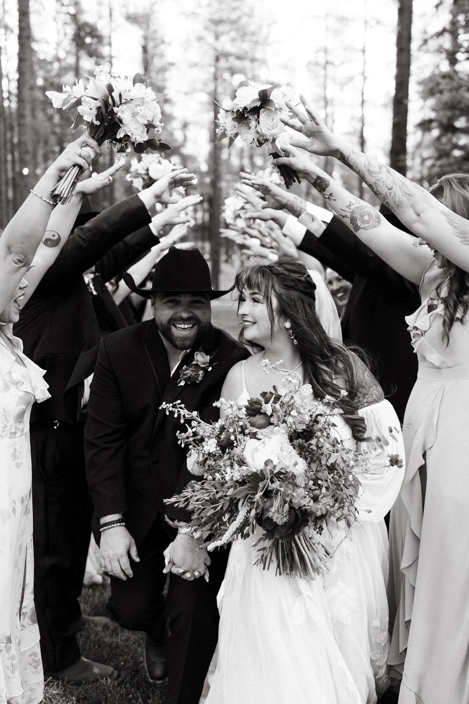 Wedding celebration in a forest with guests throwing flower petals over the newlyweds.