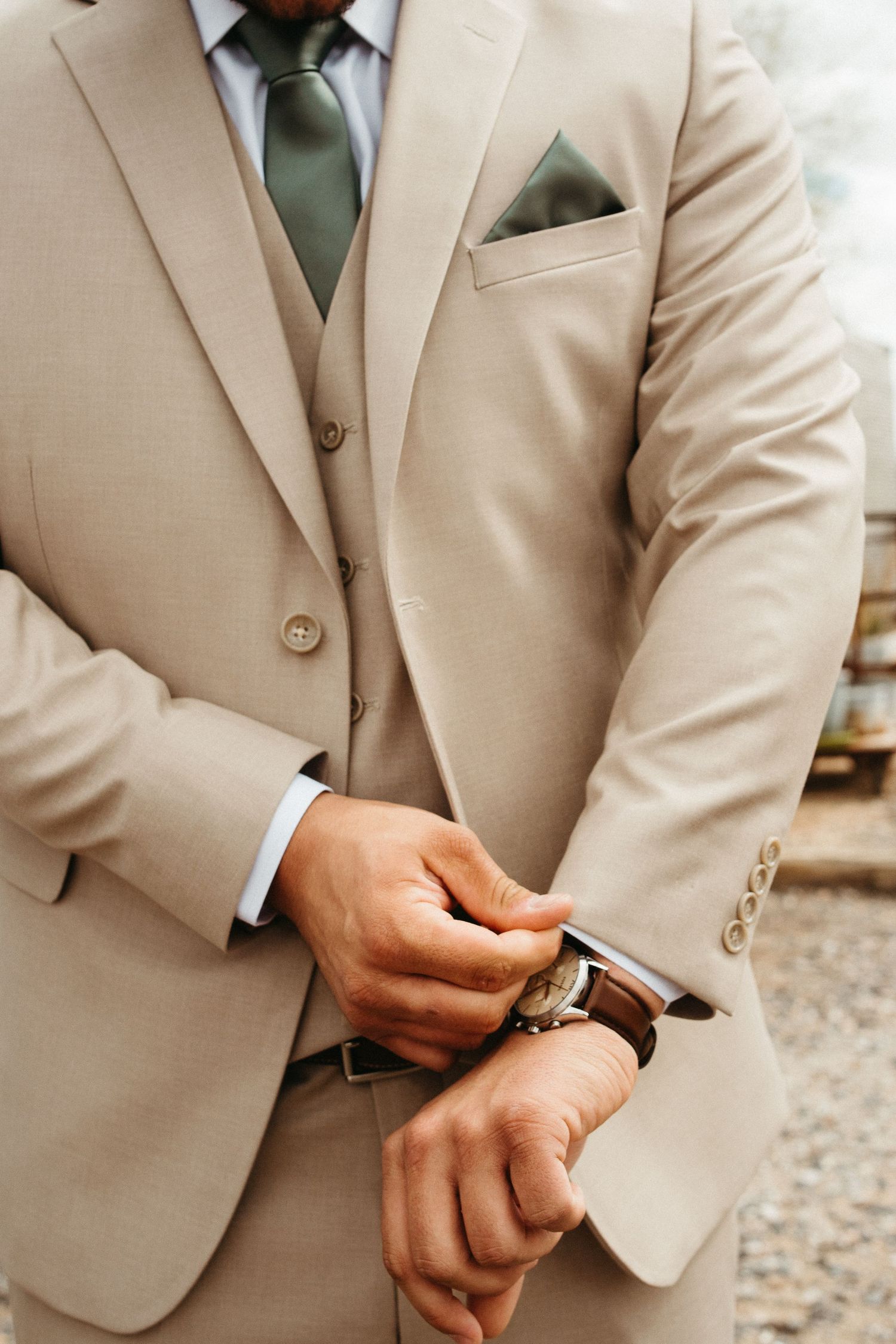 Detail shot of beige three-piece suit with sage green tie and pocket square.
