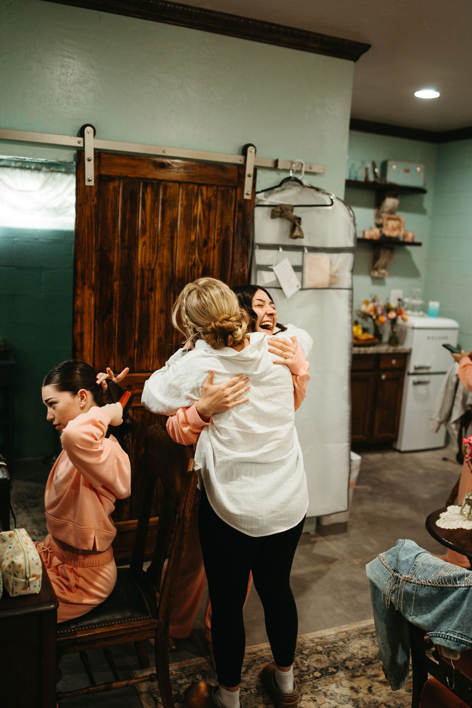 Emotional group embrace in a rustic room with mint green walls and wooden sliding door.