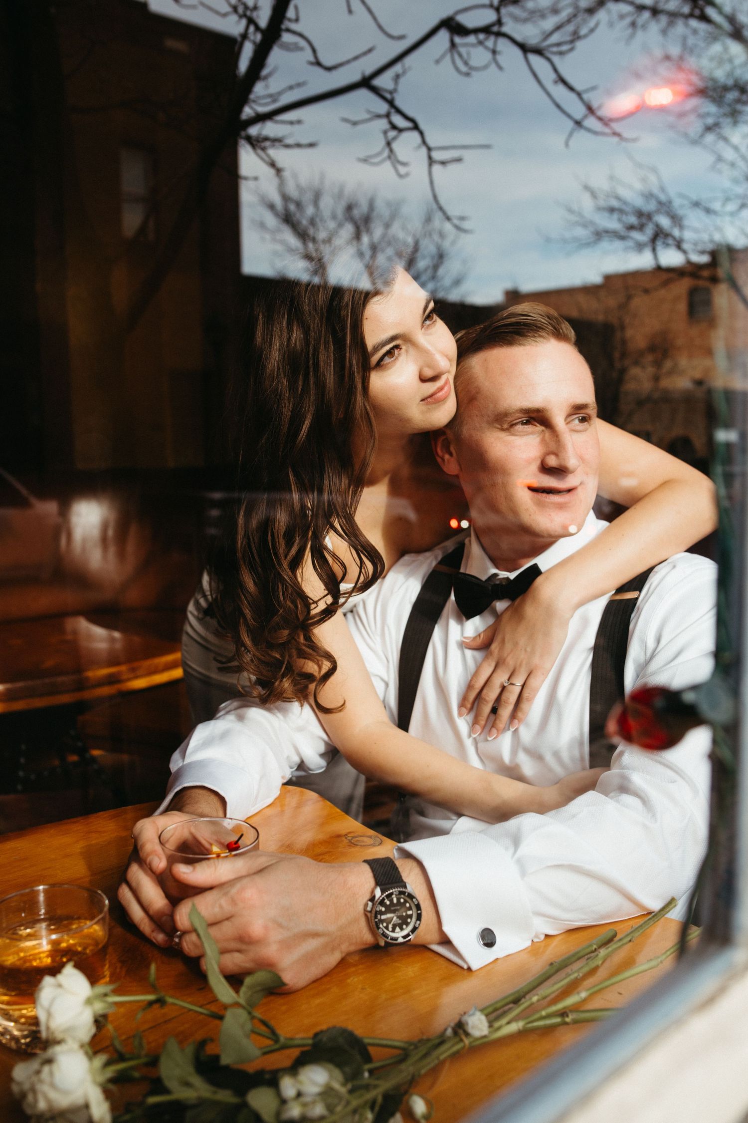 Romantic couple in formal attire sharing an intimate moment at a bar with wine glasses.