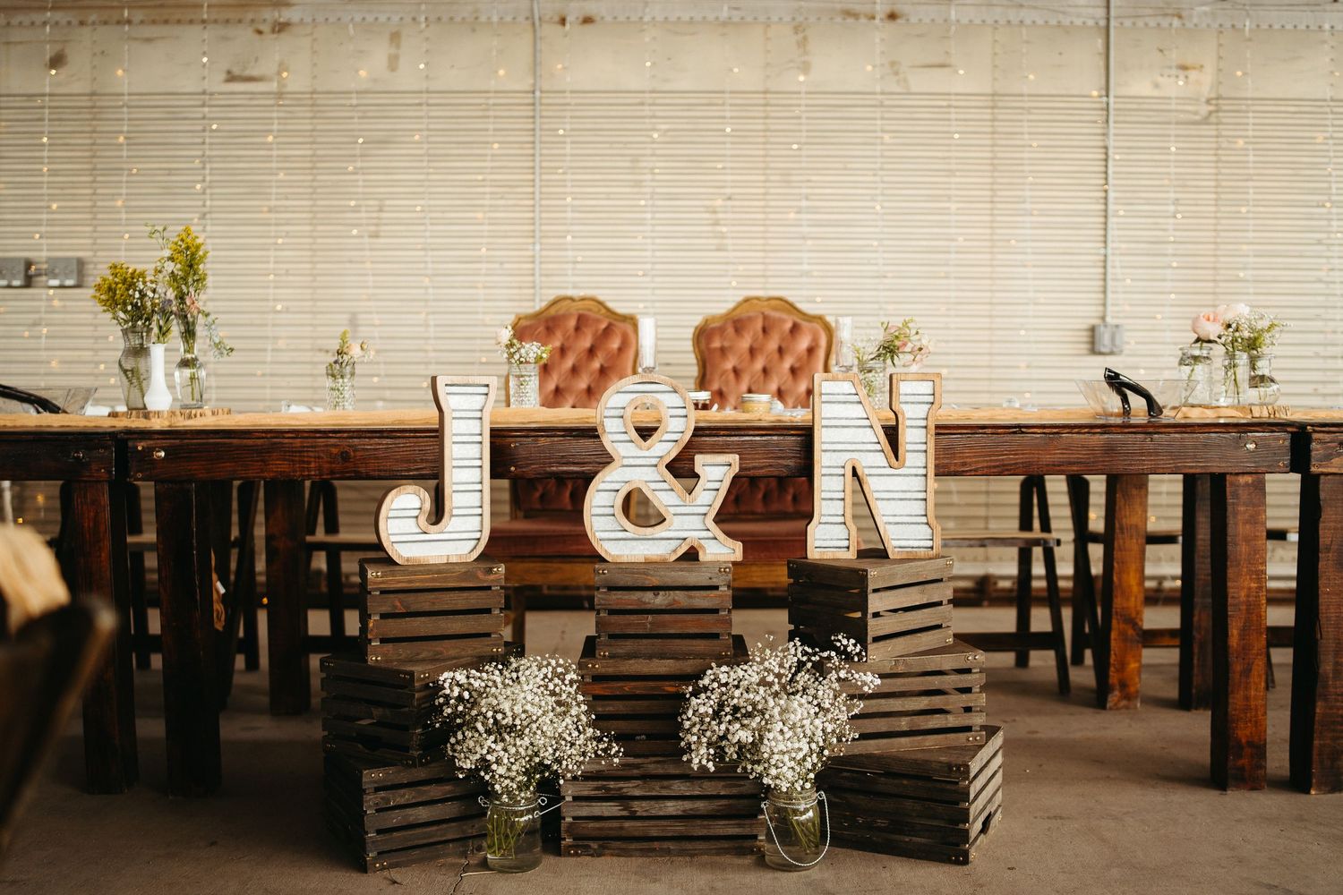 Rustic wedding decor featuring large wooden J & N letters with baby's breath flowers.