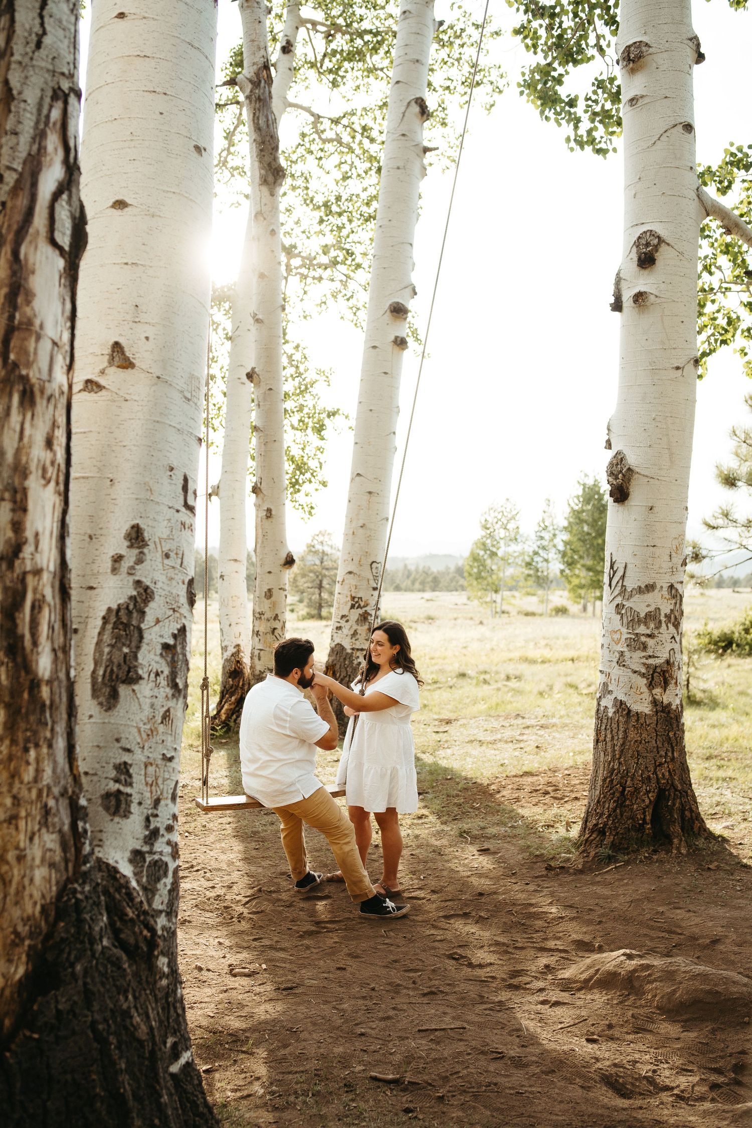 Sweet interaction between couple among white birch trees during golden hour.