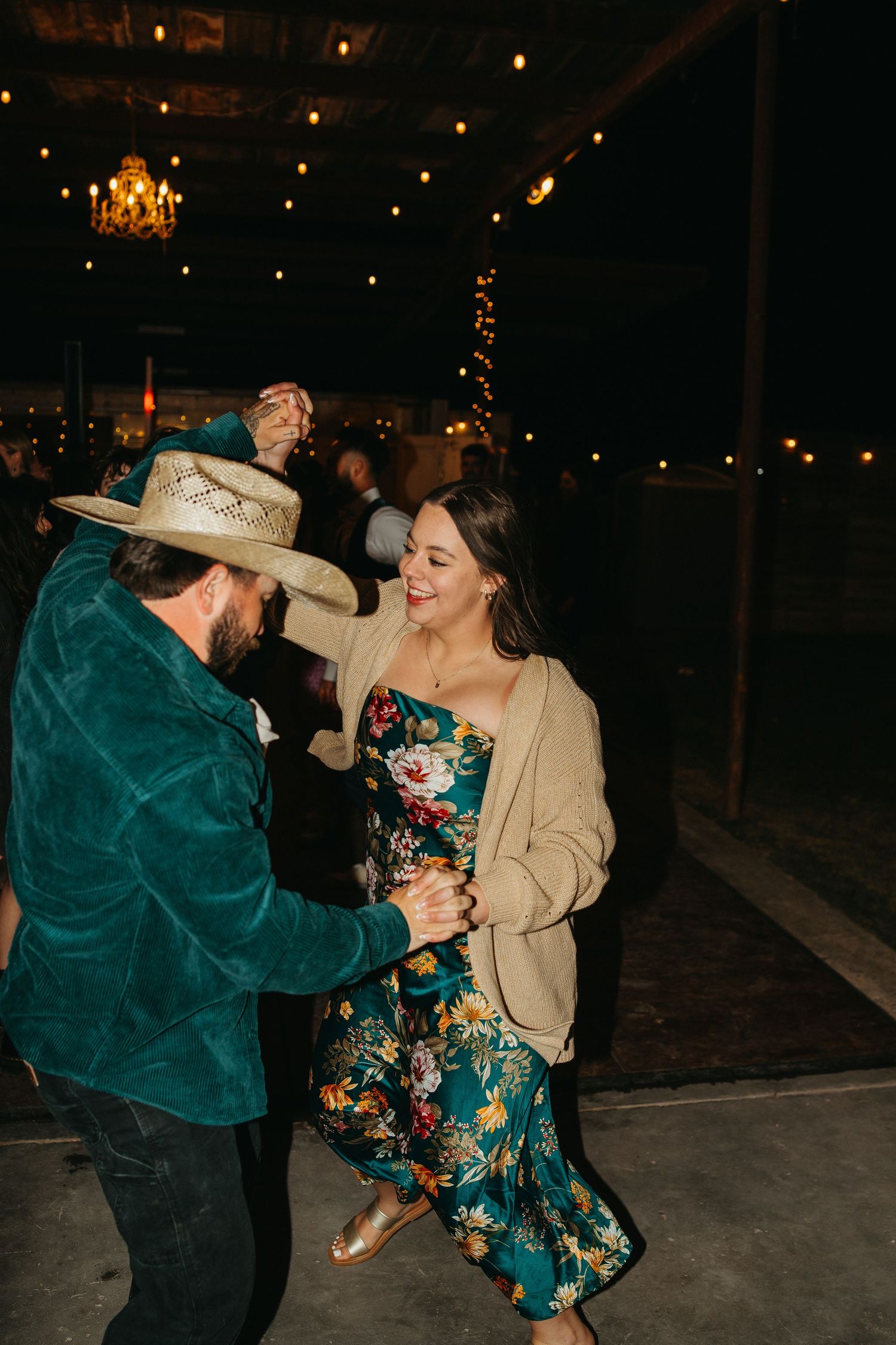 Guests dancing at a wedding reception, with one wearing a green velvet jacket and cowboy hat.