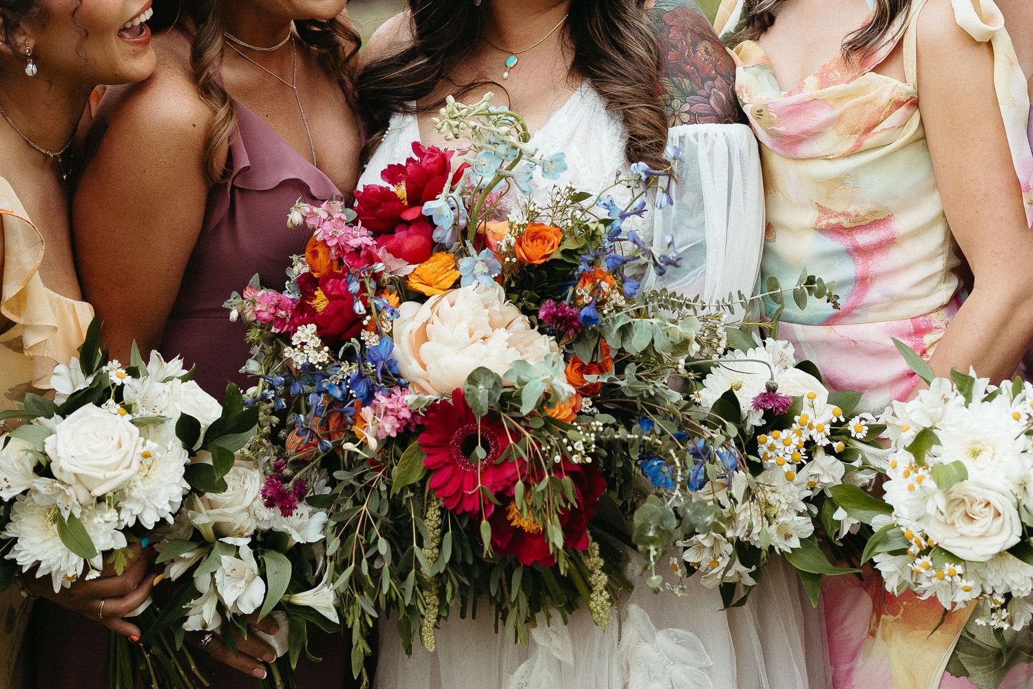 Colorful wedding bouquets featuring bright pink, white and orange flowers arranged in a row.