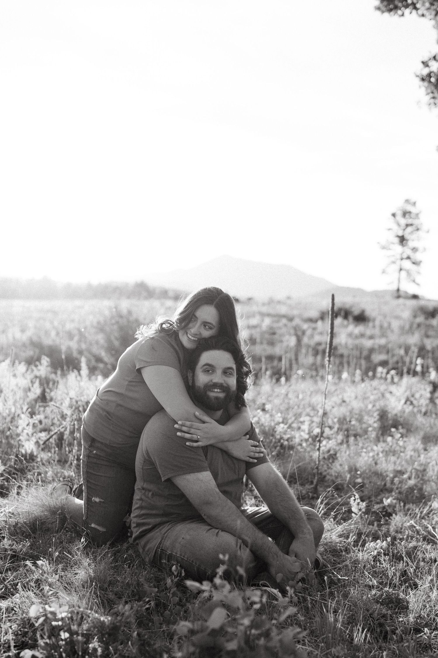A tender embrace captured in black and white photography in a rustic outdoor setting.