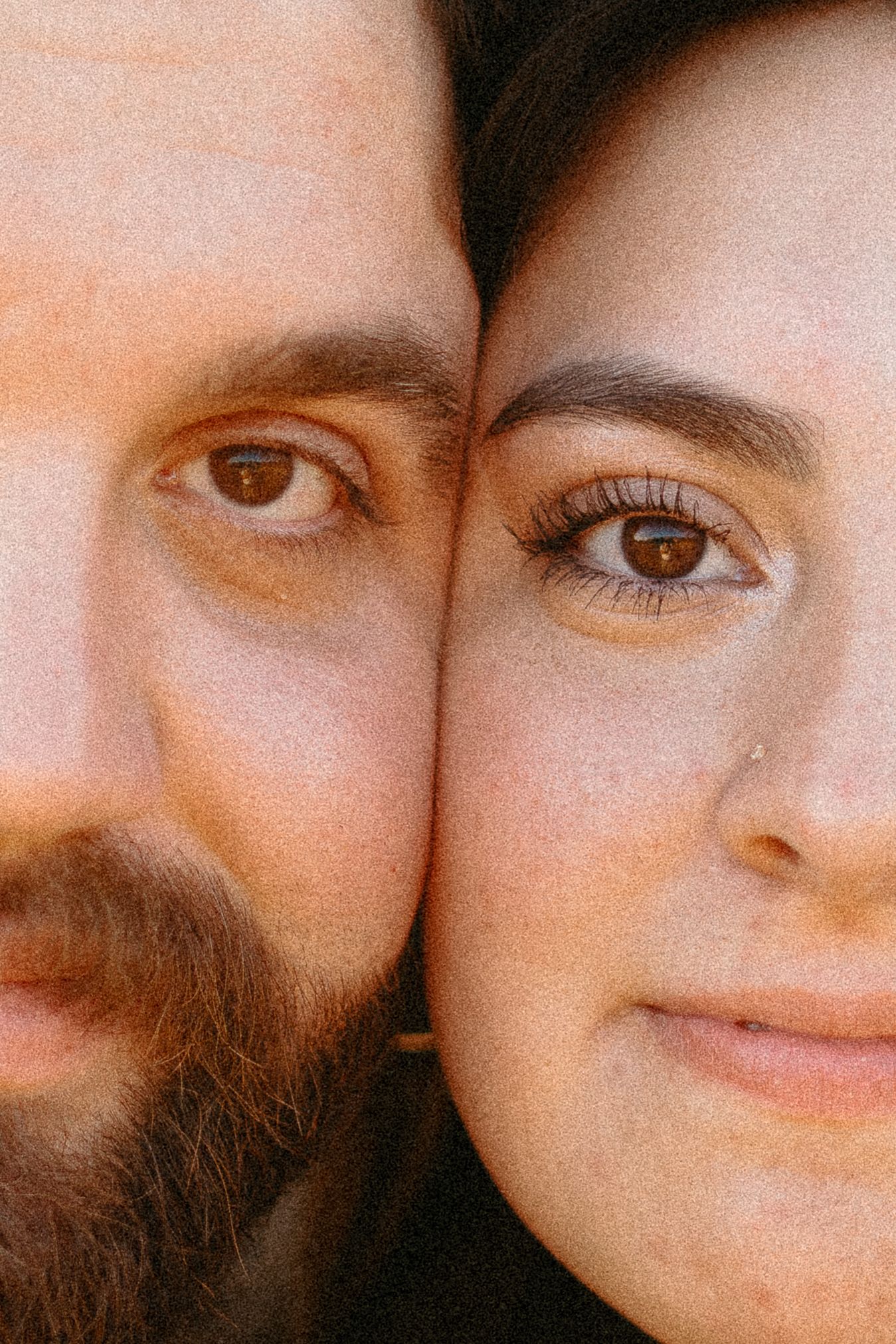 An intimate close-up portrait showcasing two faces side by side with warm lighting.