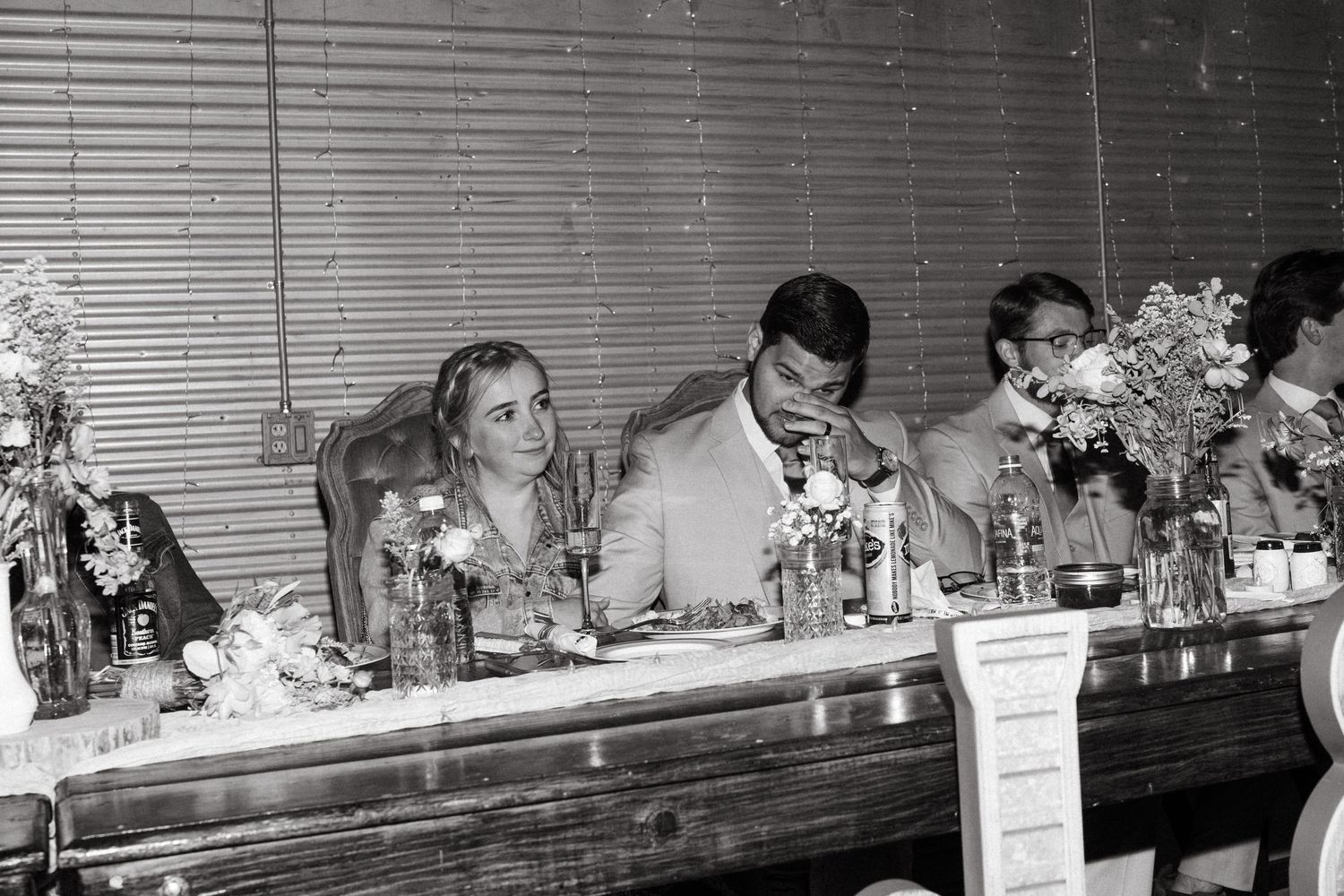 A vintage black and white photo of a wedding reception with guests seated at a head table.