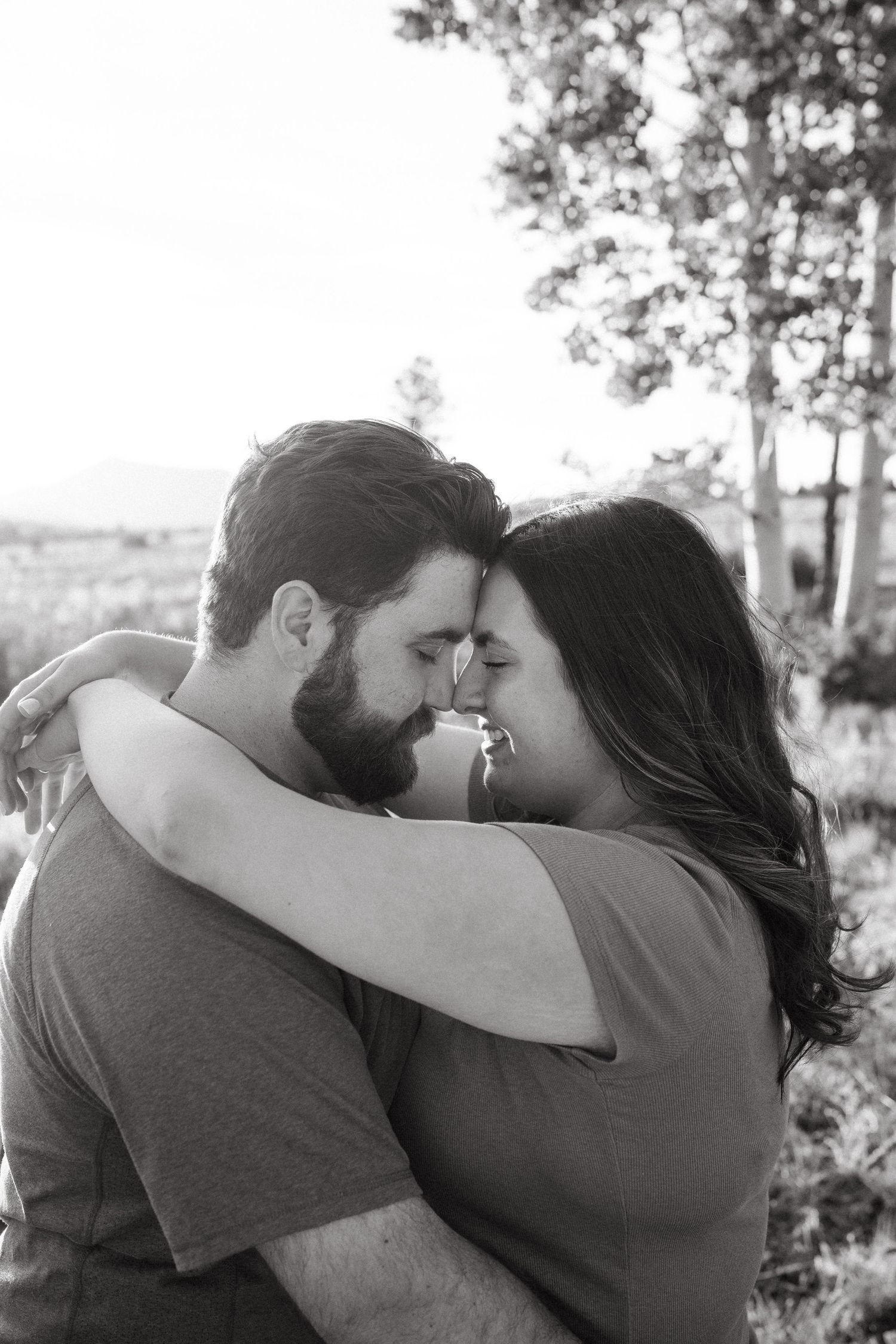 Intimate close-up portrait of a couple embracing outdoors in soft natural light.