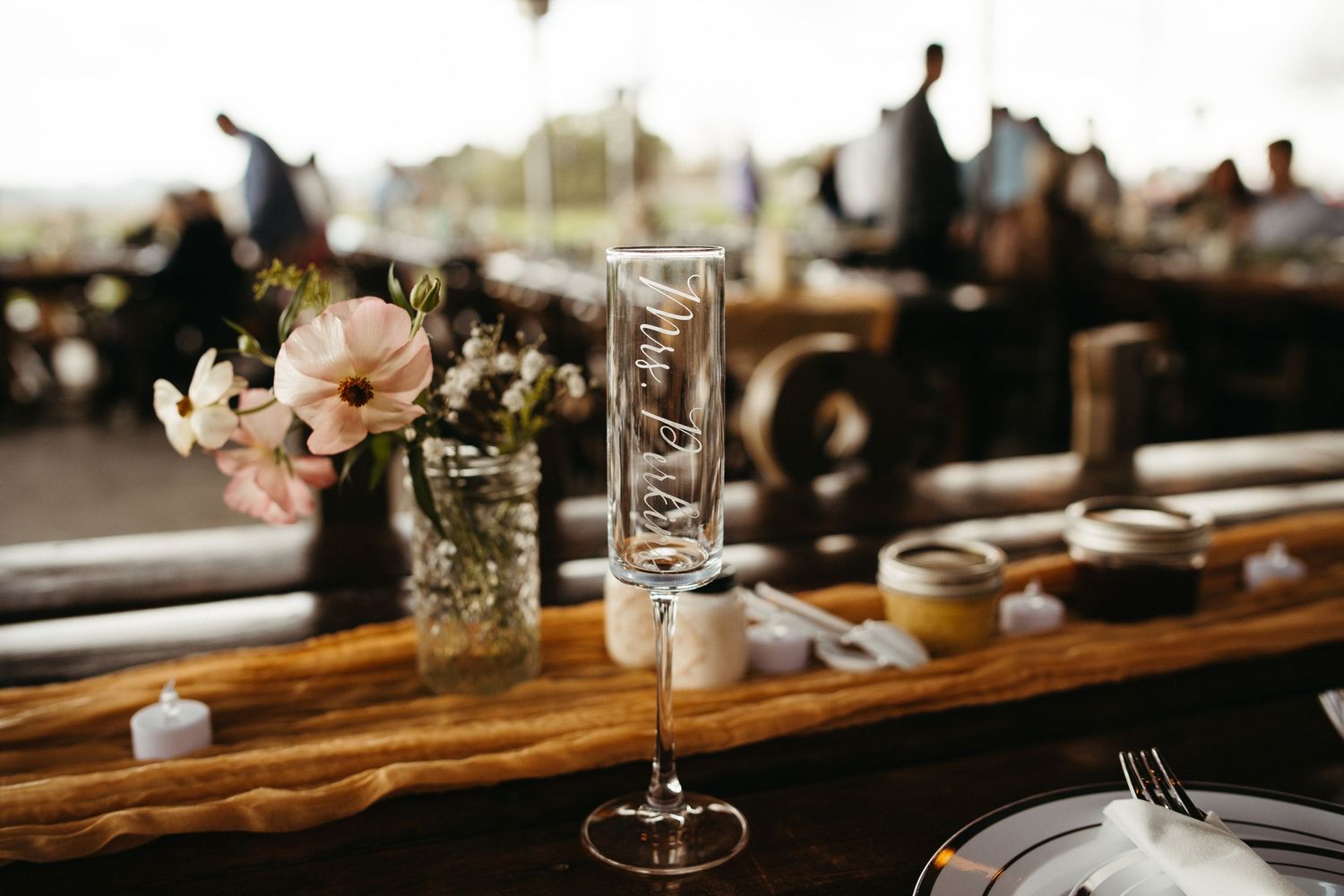 Wedding reception table setting with champagne flute and delicate floral centerpiece.