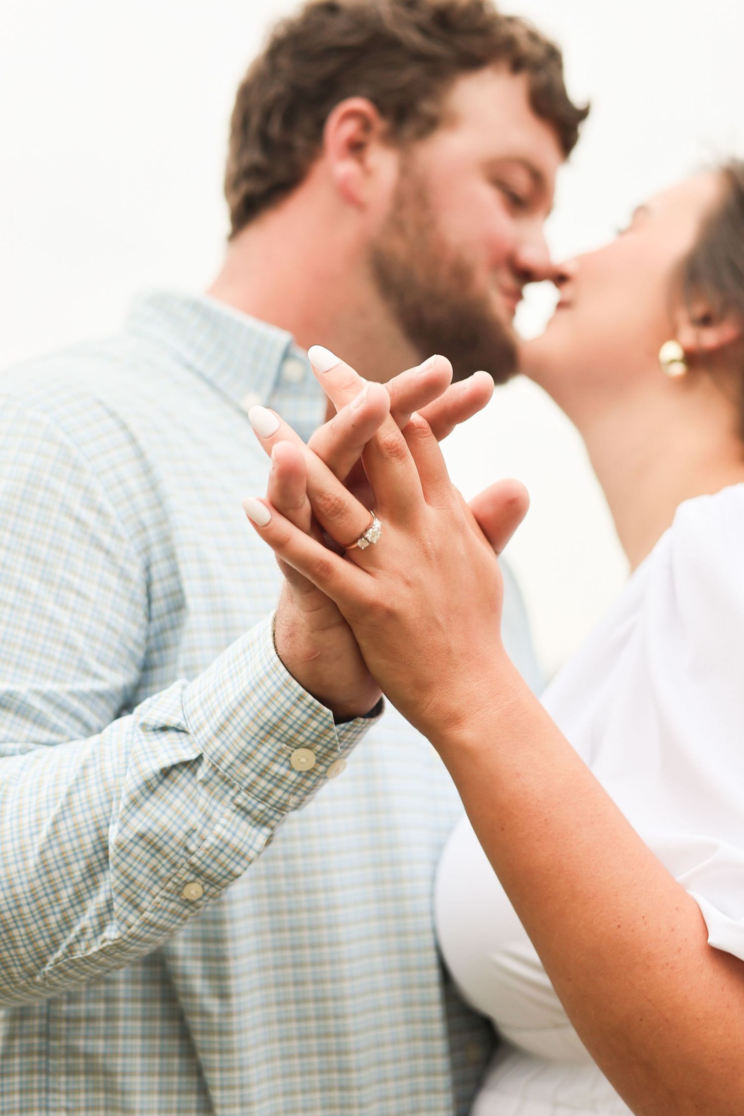 Close-up of a couple's hands with engagement ring during an intimate moment outdoors.