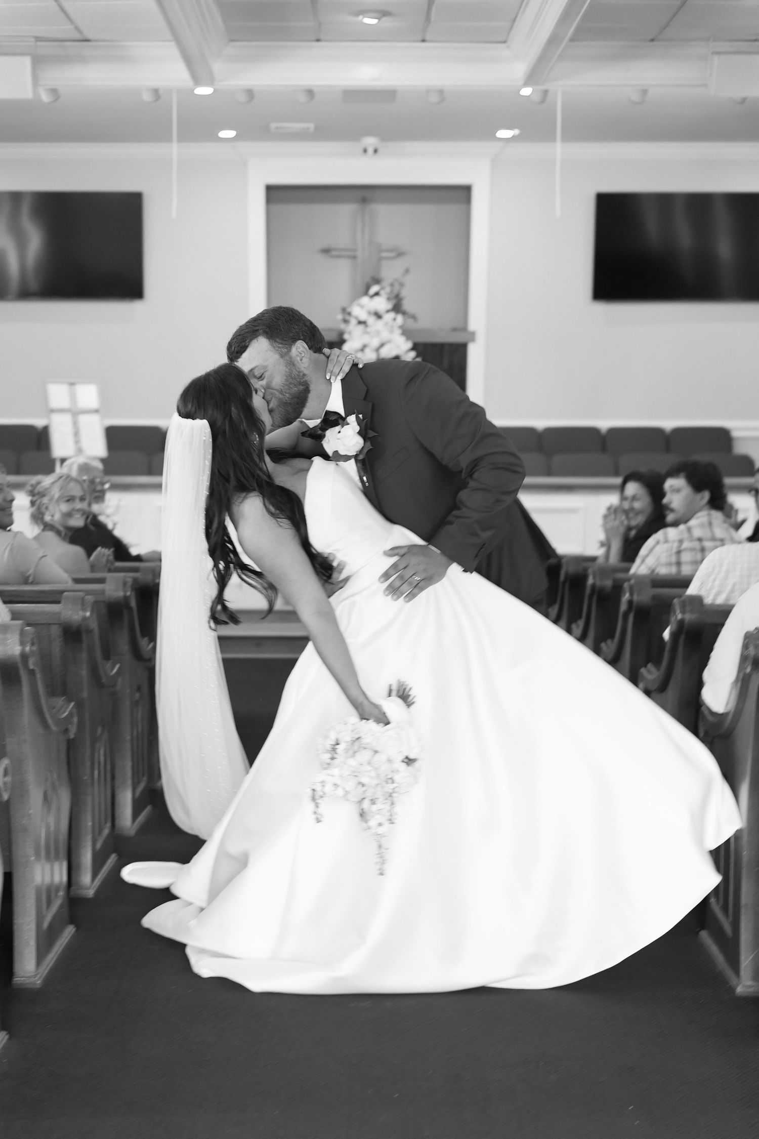 Bride and groom share a romantic dip kiss at the altar inside a church during their wedding ceremony.