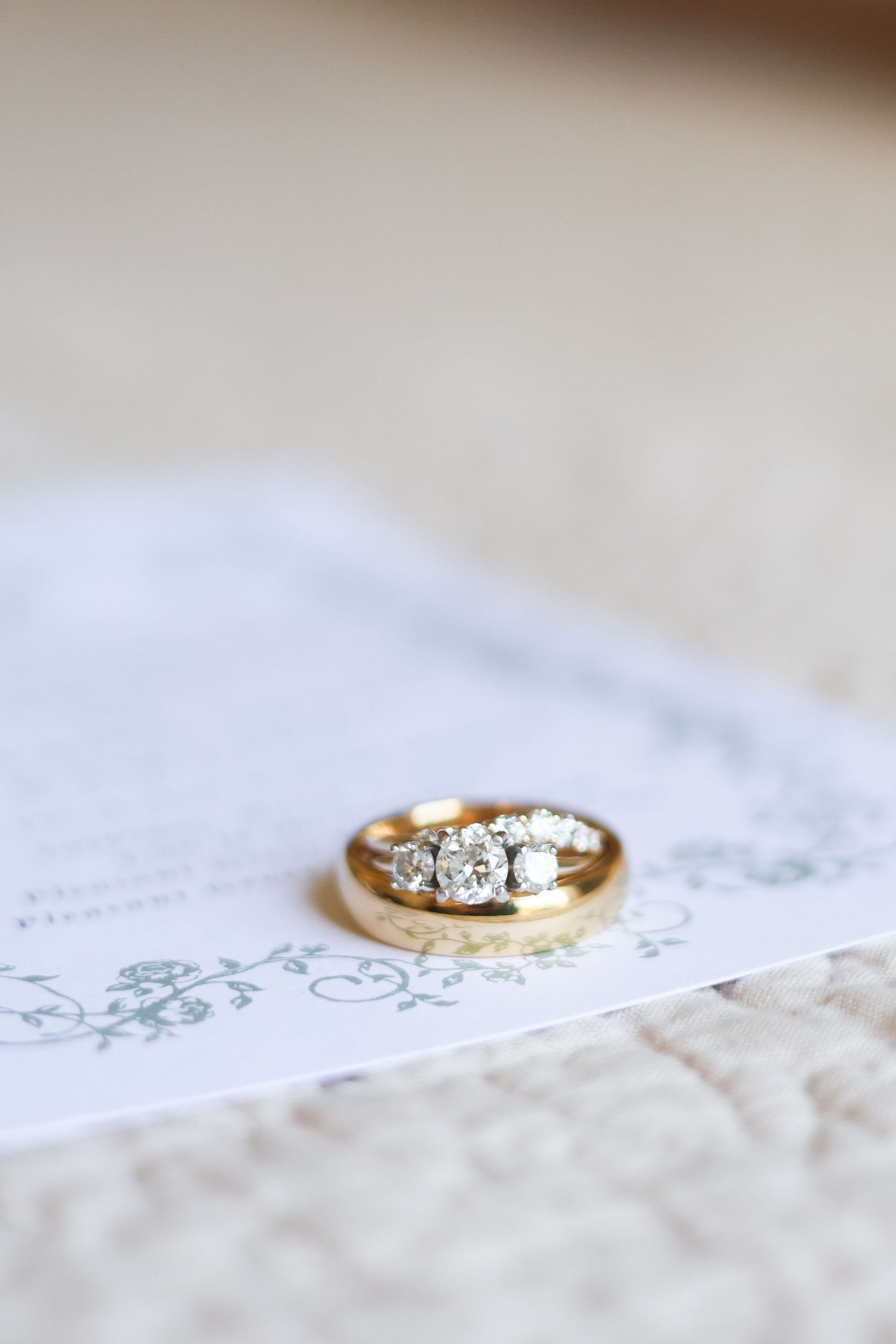Diamond engagement ring in gold setting photographed on textured white lace background with soft lighting.