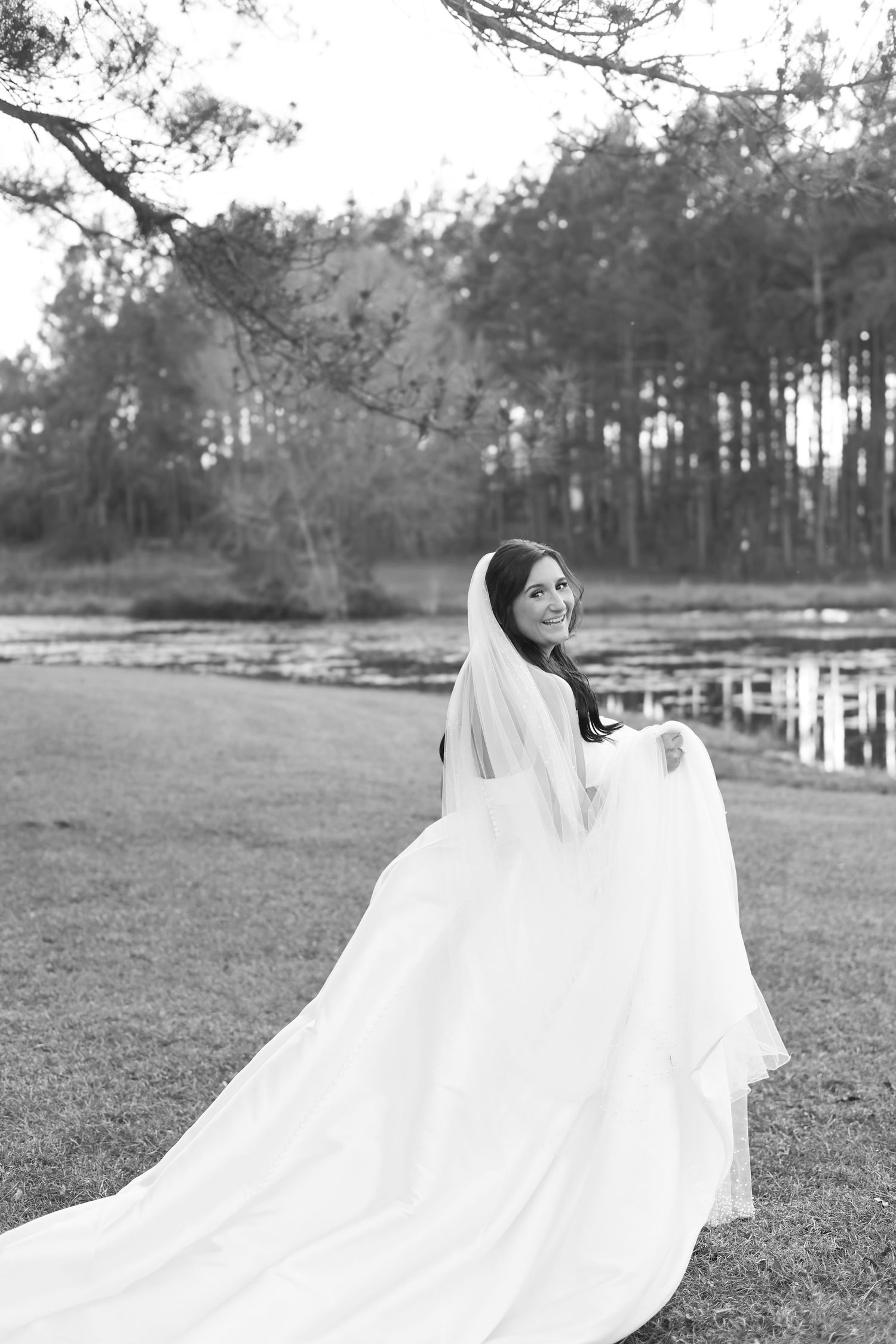 Black and white wedding photos capture bride's dress flowing dramatically in outdoor forest setting.
