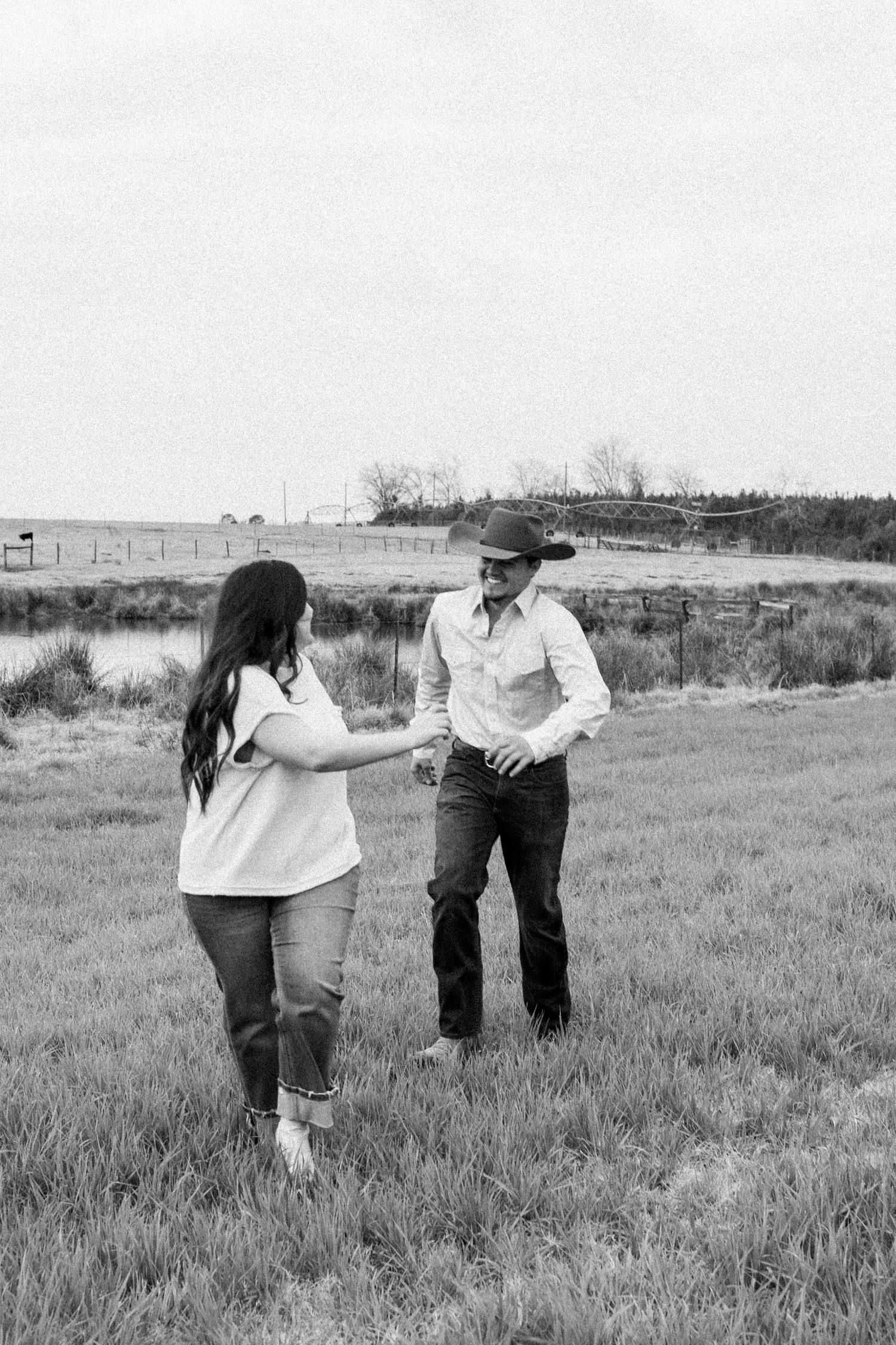 A couple having a playful moment together in an open countryside setting.